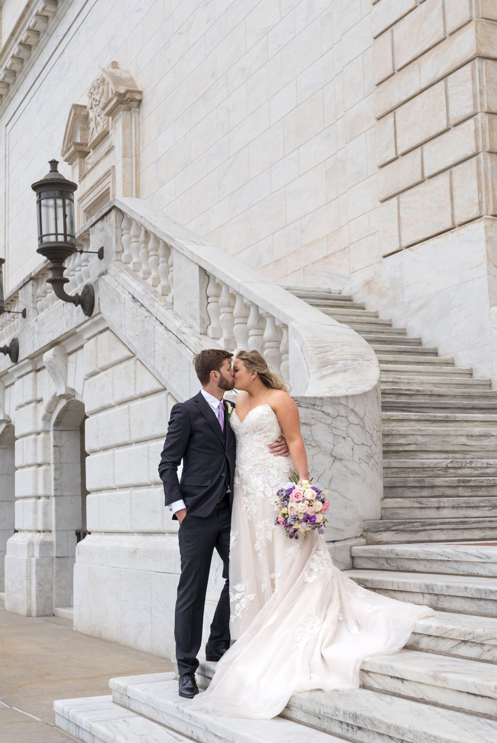 A bride  and groom kiss on the steps of the Detroit Institute of Art.  