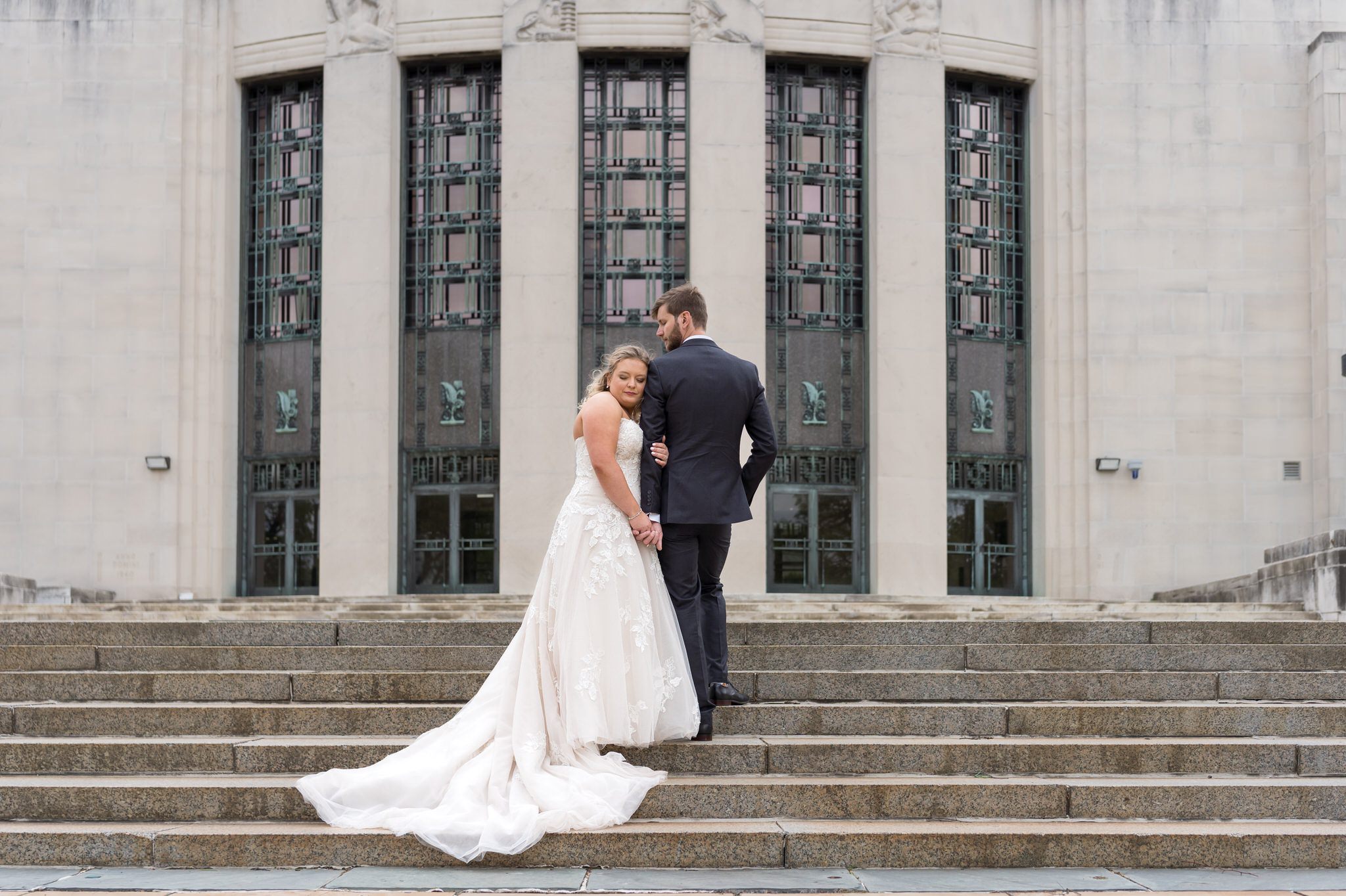 A bride and groom pose on the steps of the Horace H. Rackham Educational Memorial on their wedding day.  