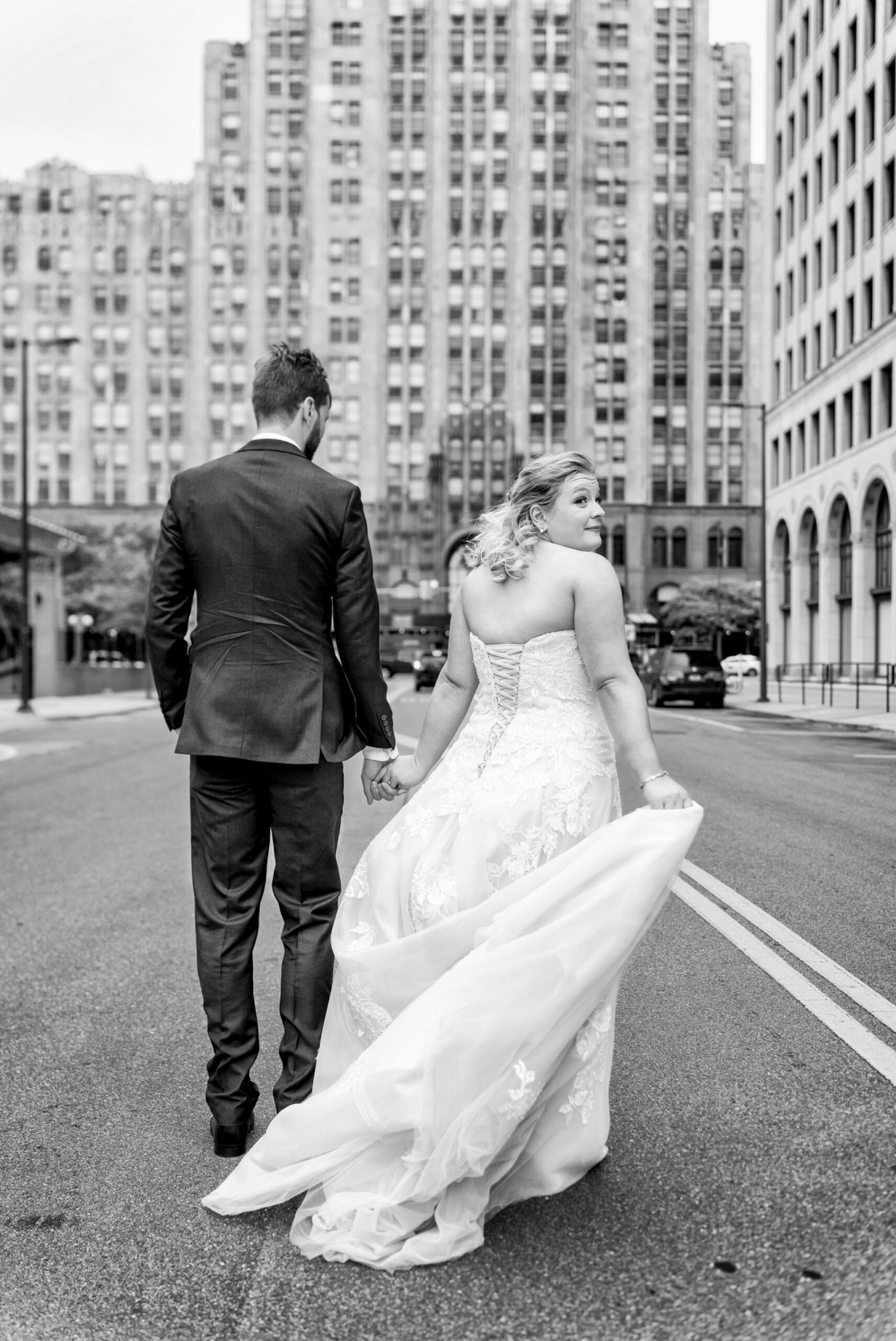 A bride looks over her shoulder in front of the  the Fisher Building on her wedding day.  