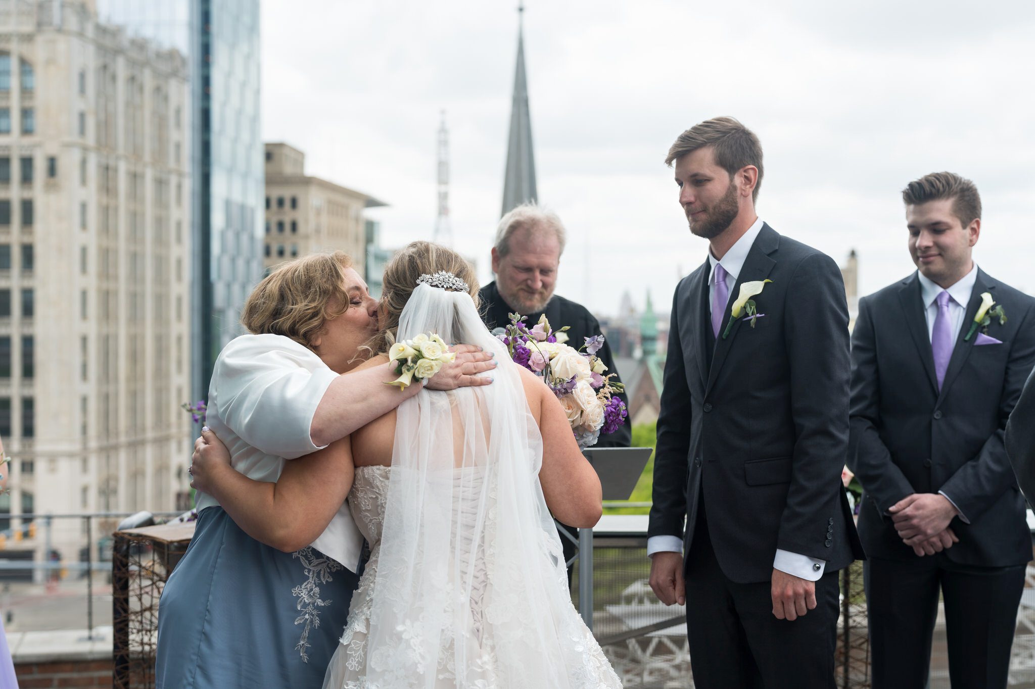 The mother of the bride kisses her daughter and gives away her hand during a Madison Building wedding. 