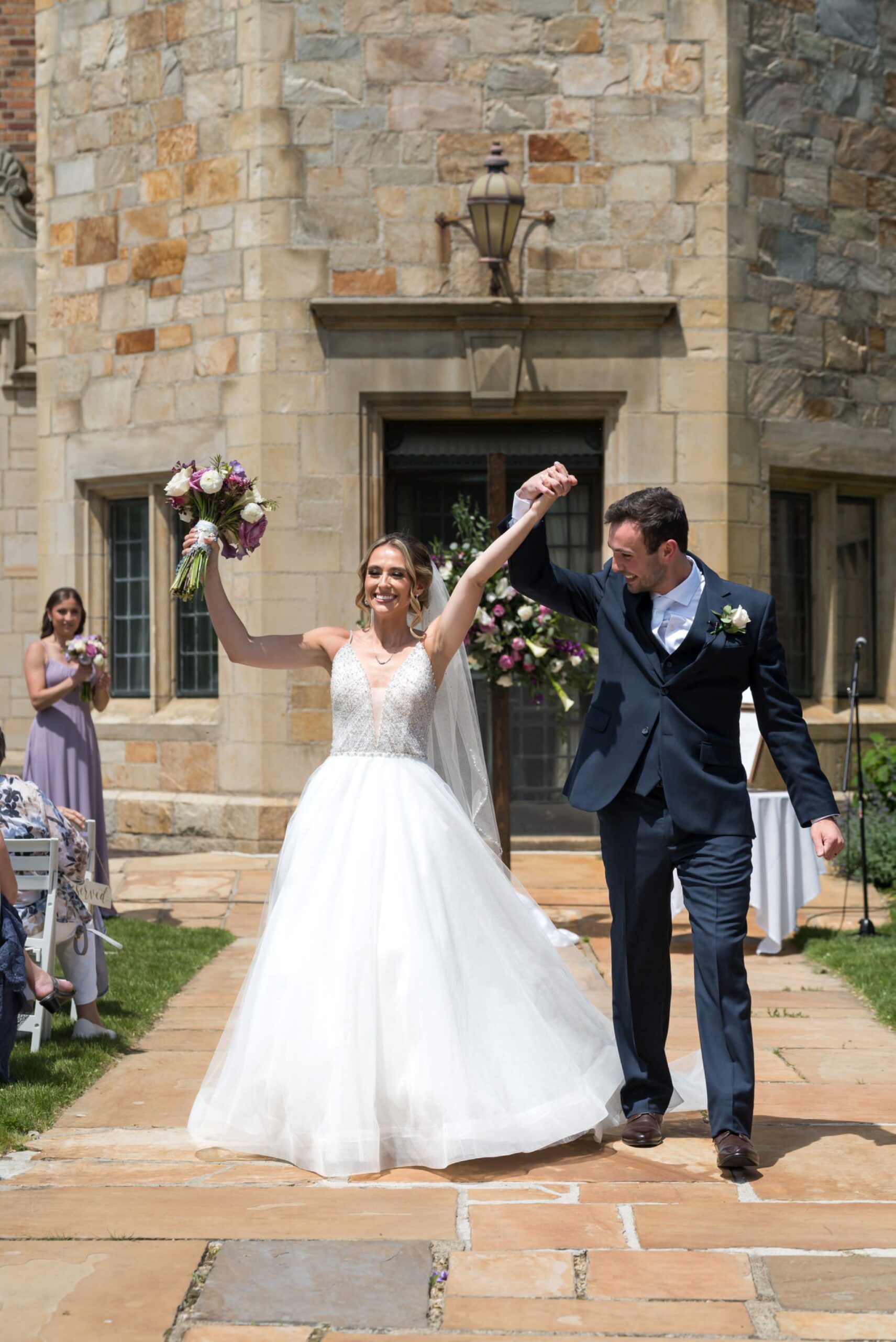 Bride and groom celebrate as they walk down the aisle at their wedding at Meadowbrook Hall in the Pegasus Garden. 