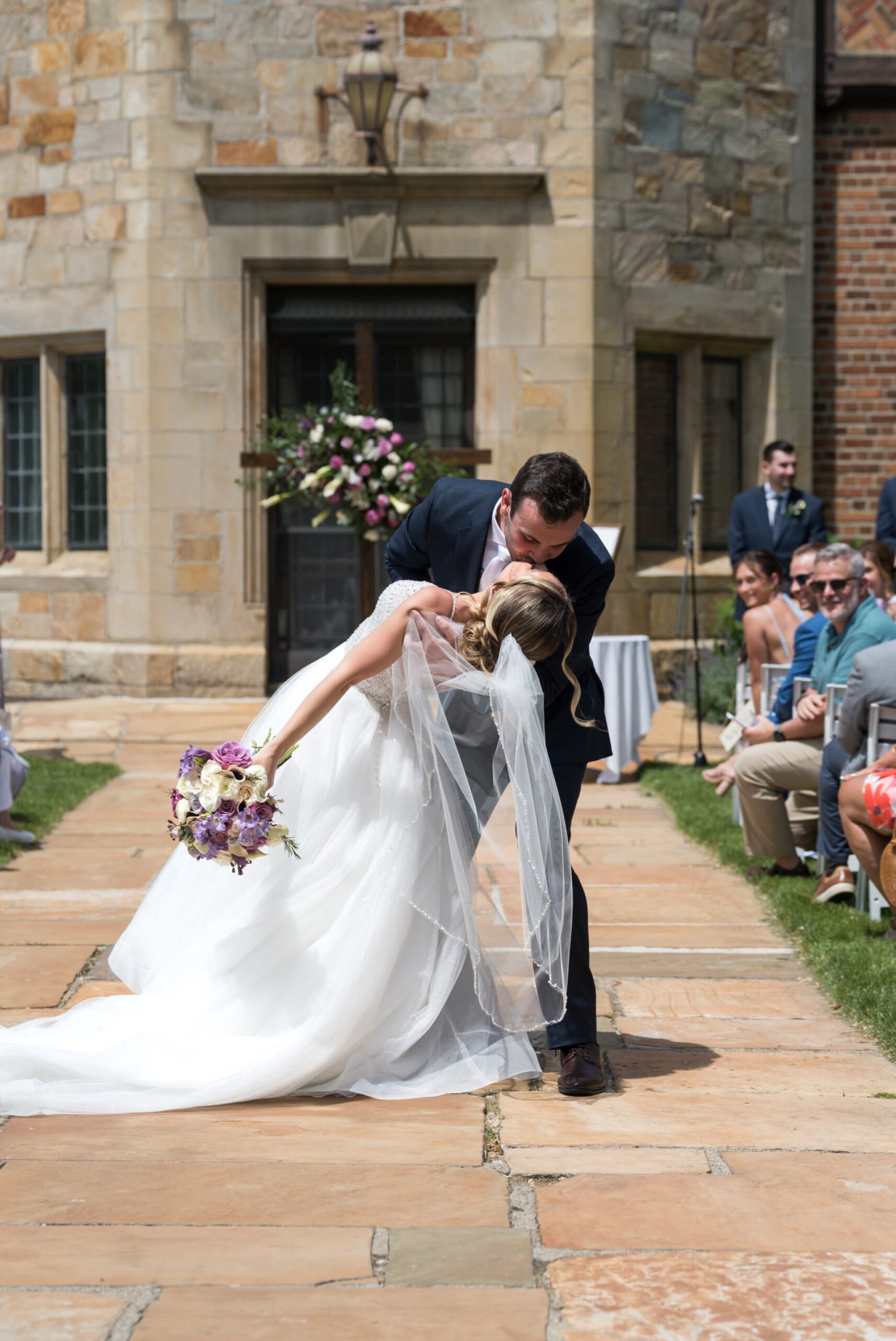 Bride and groom celebrate and kiss as they walk down the aisle at their wedding at Meadowbrook Hall in the Pegasus Garden. 
