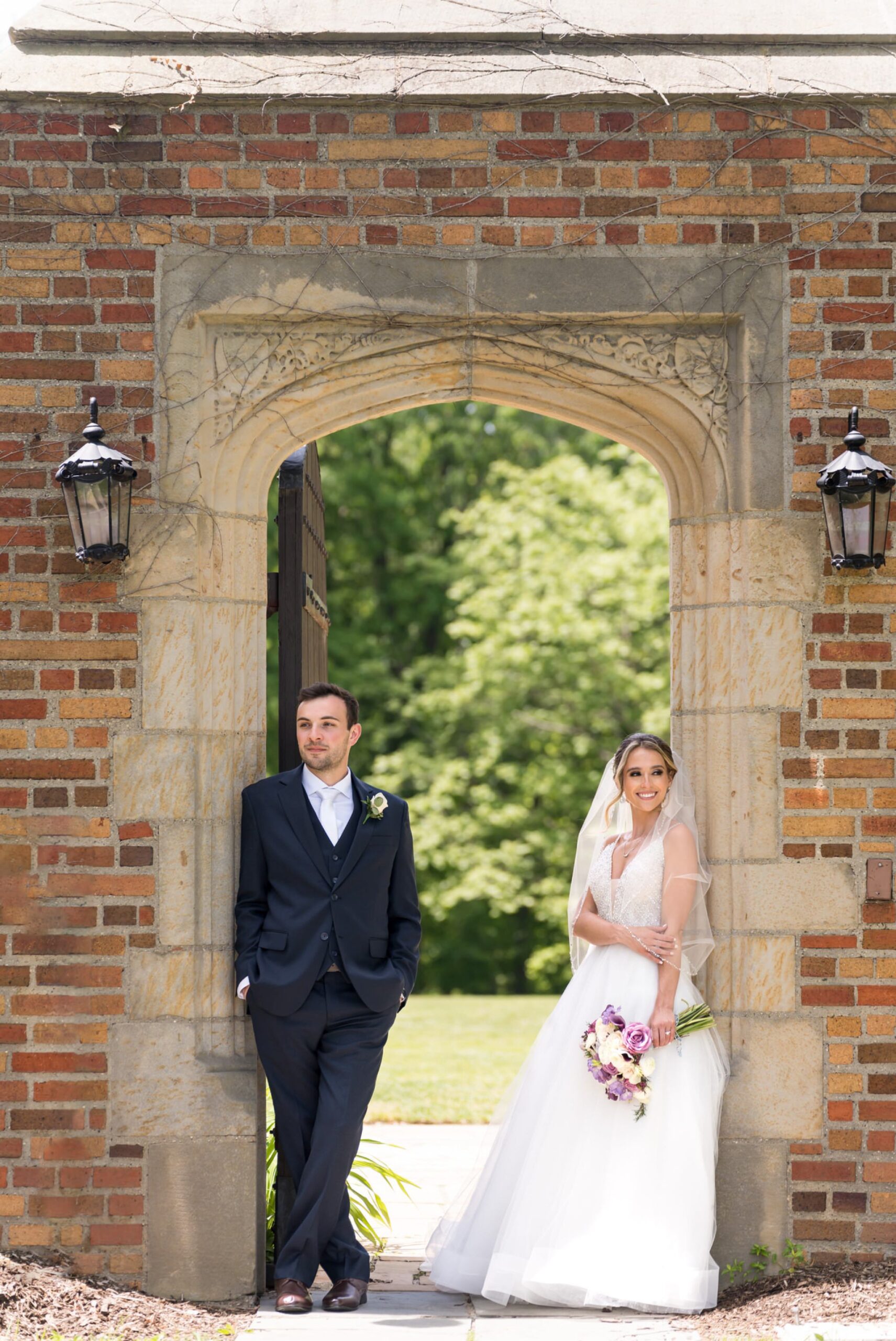 A bride and groom pose in an archway at their wedding at Meadowbrook Hall.  