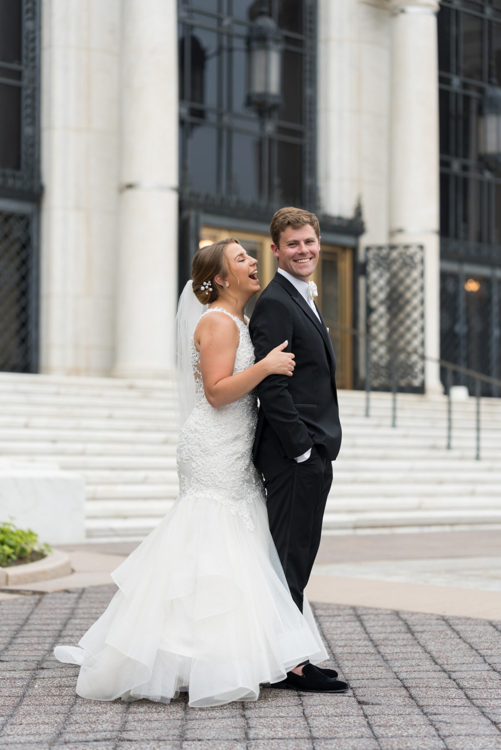 A bride and groom laugh outside of the DIA on their wedding day.   