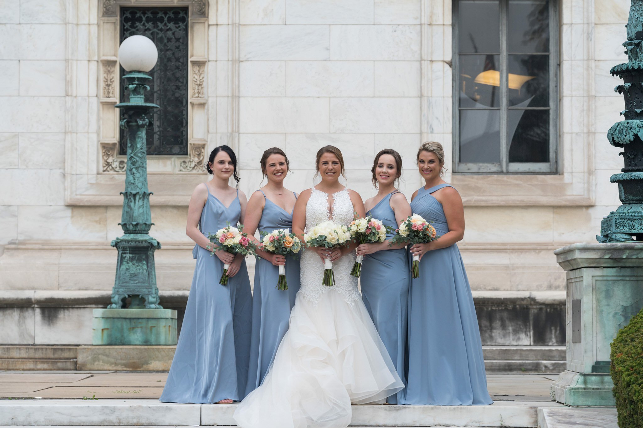 Bridesmaids, wearing pastel blue dresses, pose for formals at Detroit Public LIbrary.