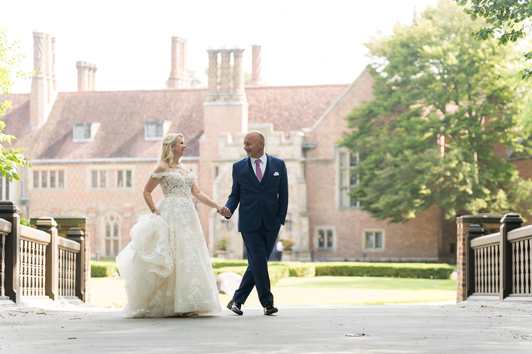 A bride and groom embrace on the bridge of Meadow Brook Hall on their wedding day.  
