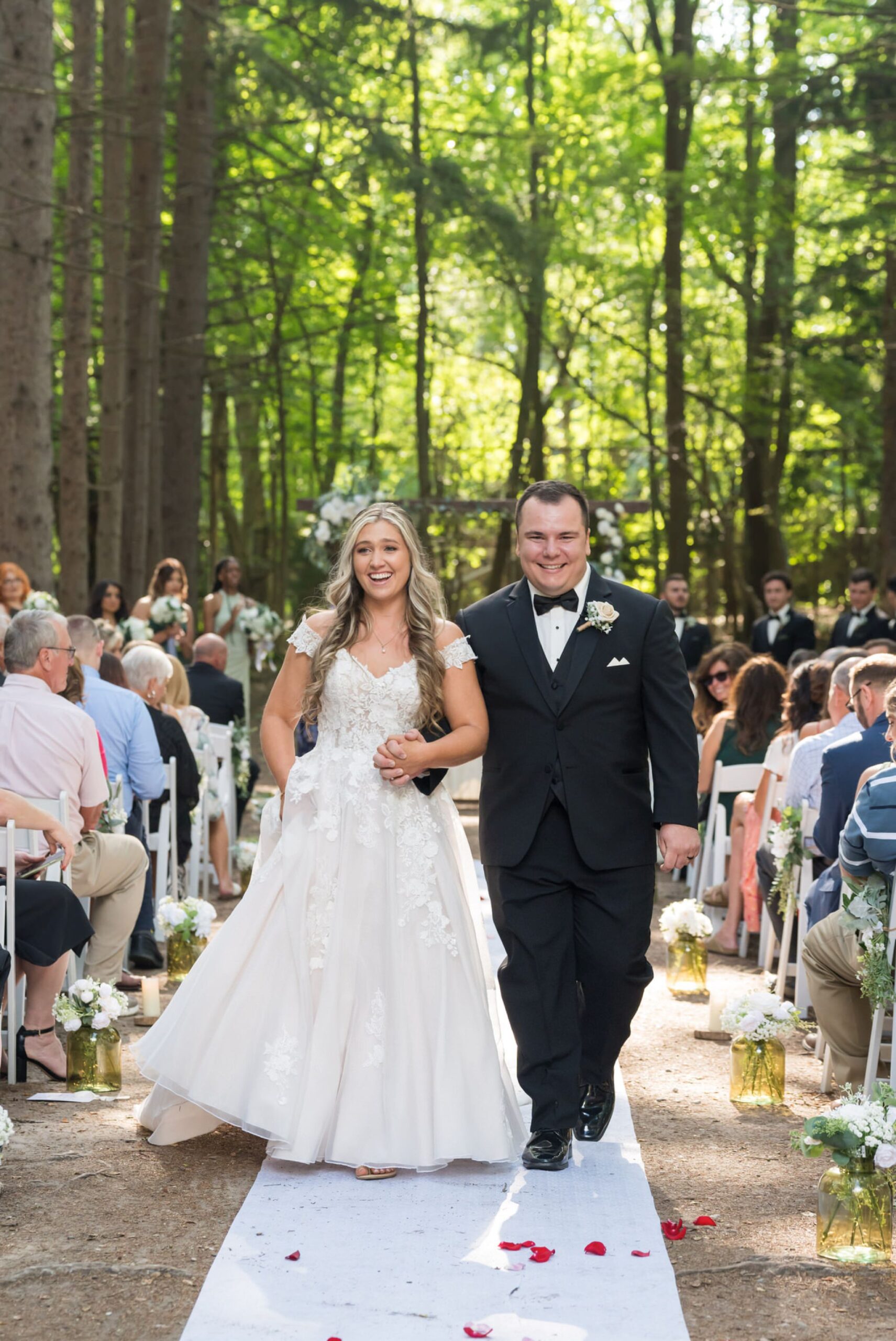 The bride and groom smile as they walk down the aisle at their Stony Creek wedding in The Pines.  