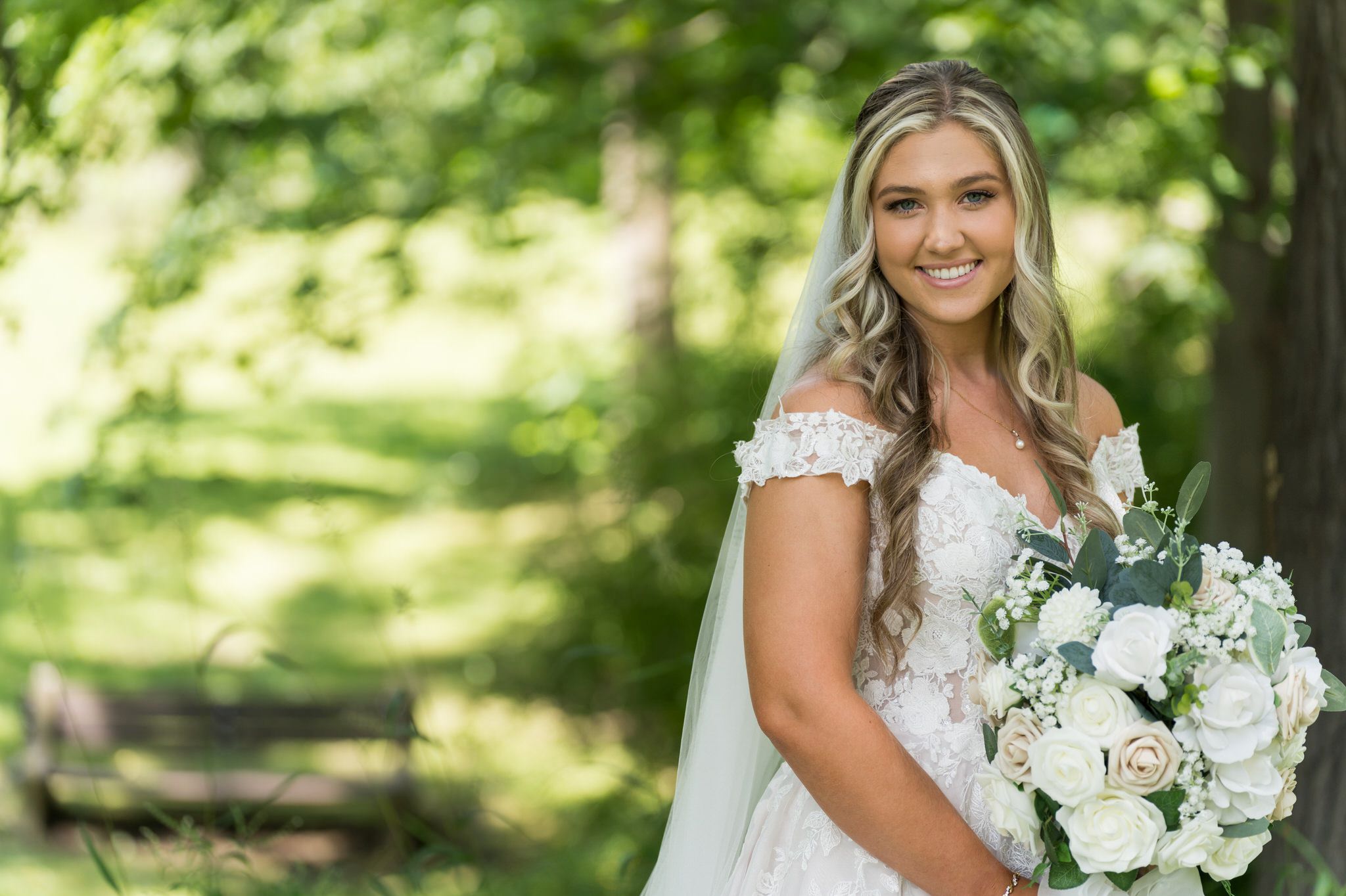 A bride smiles while holding a bouquet during her wedding at Van Hoosen in Rochester, MI. 