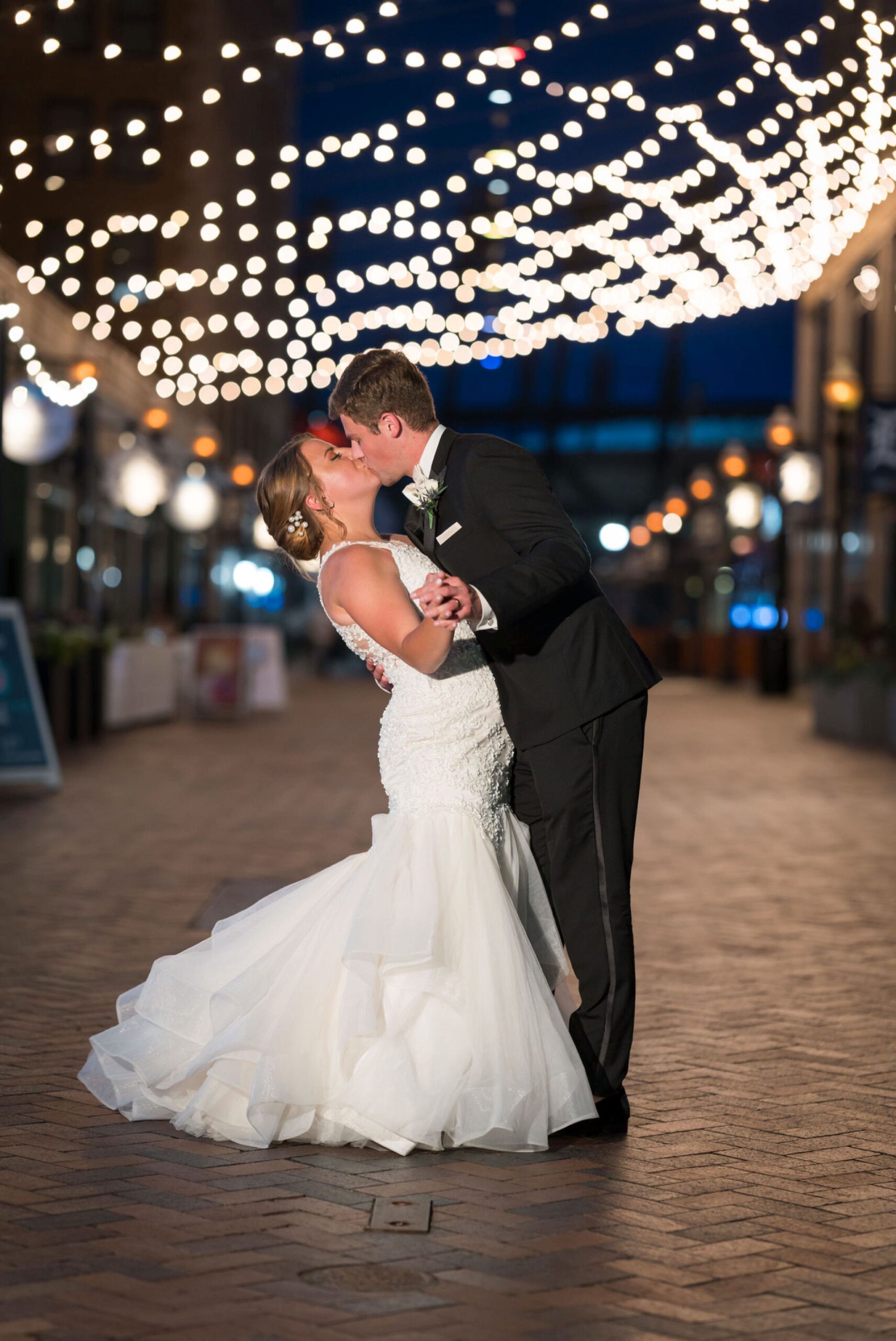 Newlyweds kiss under city lights in downtown Detroit.  