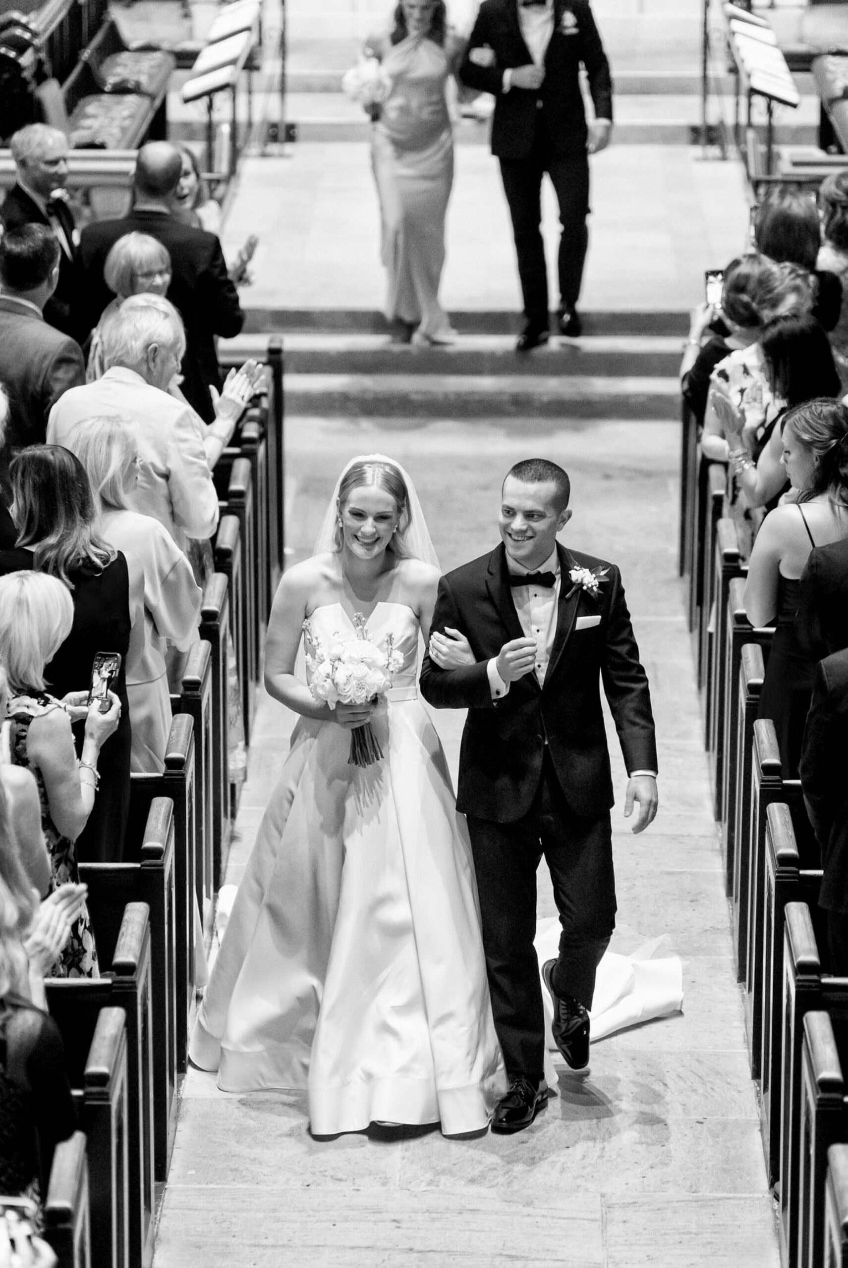 The bride and groom smile, walking down the aisle after their wedding at Christ Church Grosse Pointe.