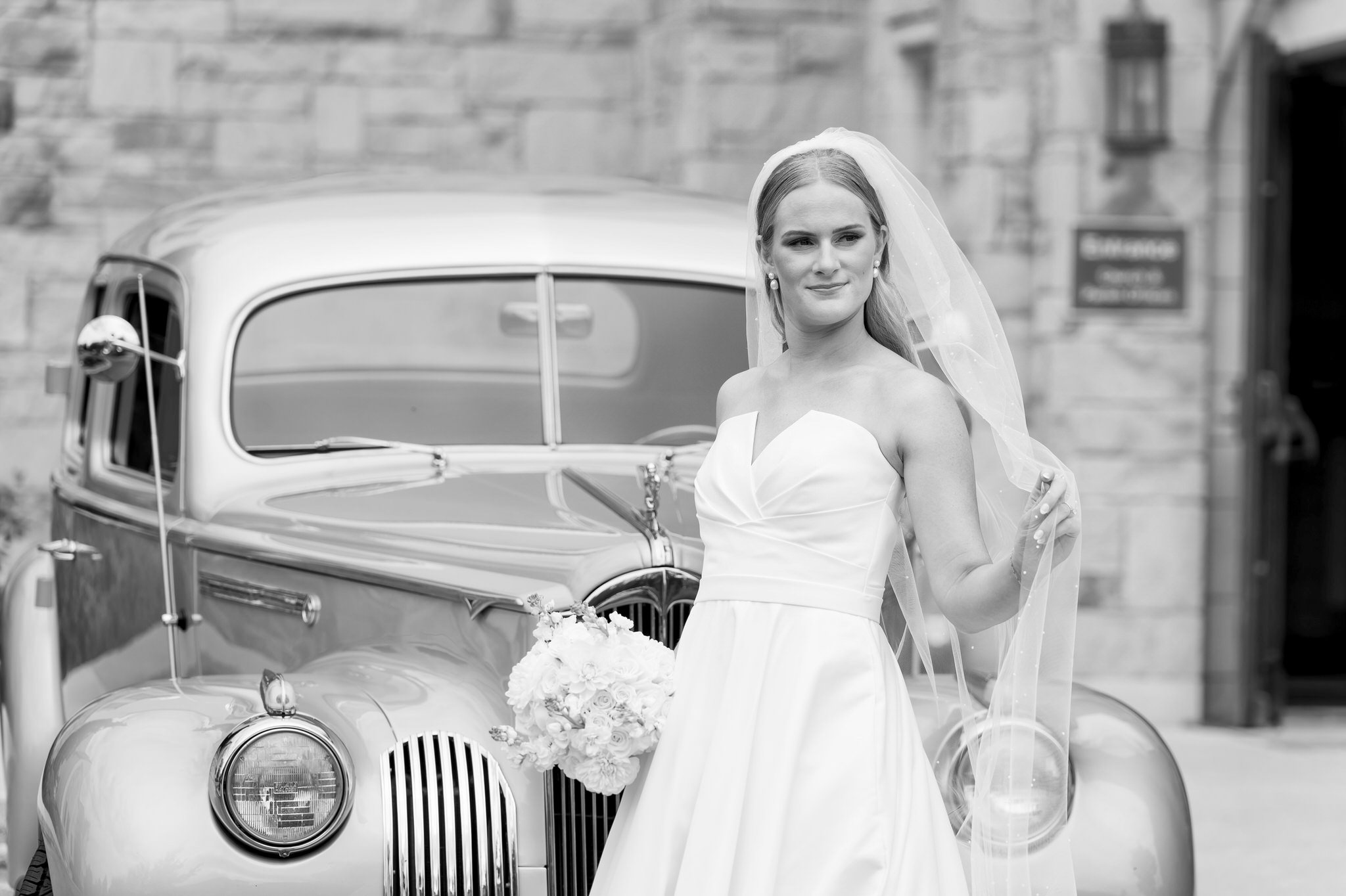 A bride poses in front of a classic Packard from Motor City Vintage Rentals.  