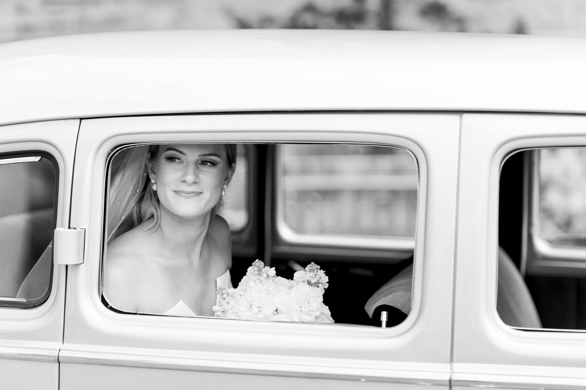 A bride smiles sitting inside of a classic Packard from Motor City Vintage Rentals.  