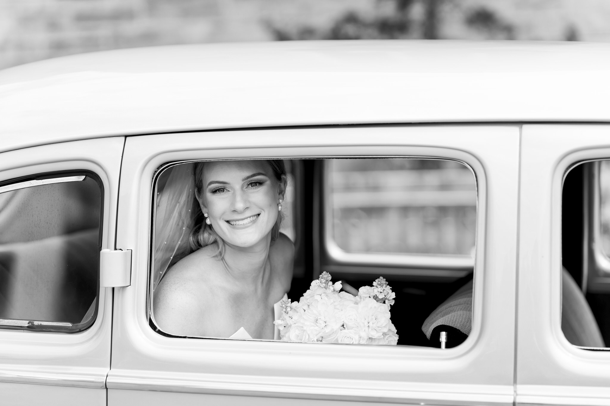 A bride smiles sitting inside of a classic Packard from Motor City Vintage Rentals.  