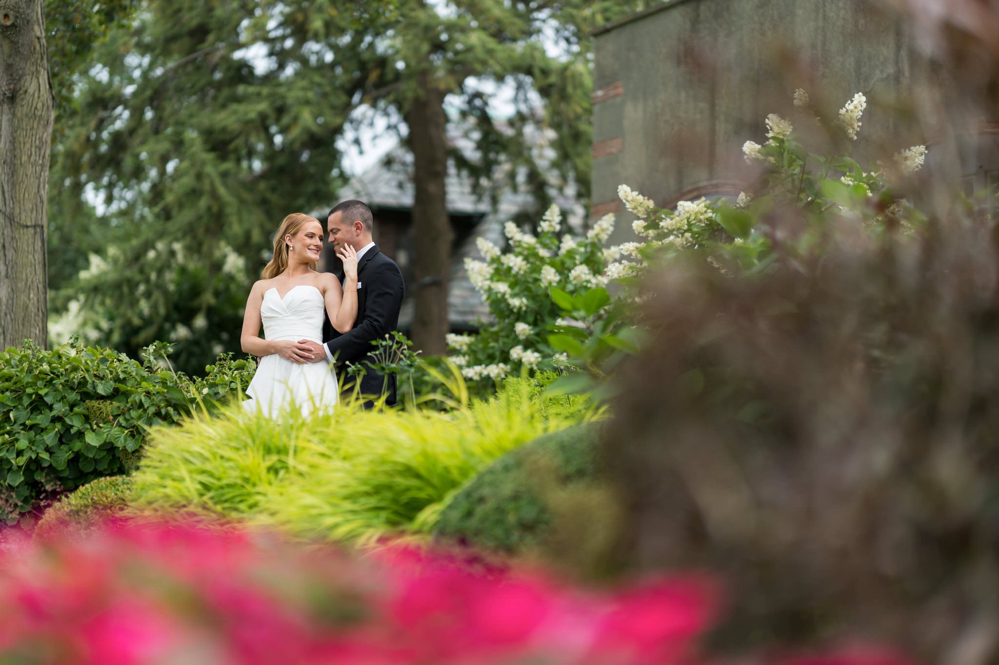 A bride and groom embrace in the gardens of their Country Club of Detroit wedding.  