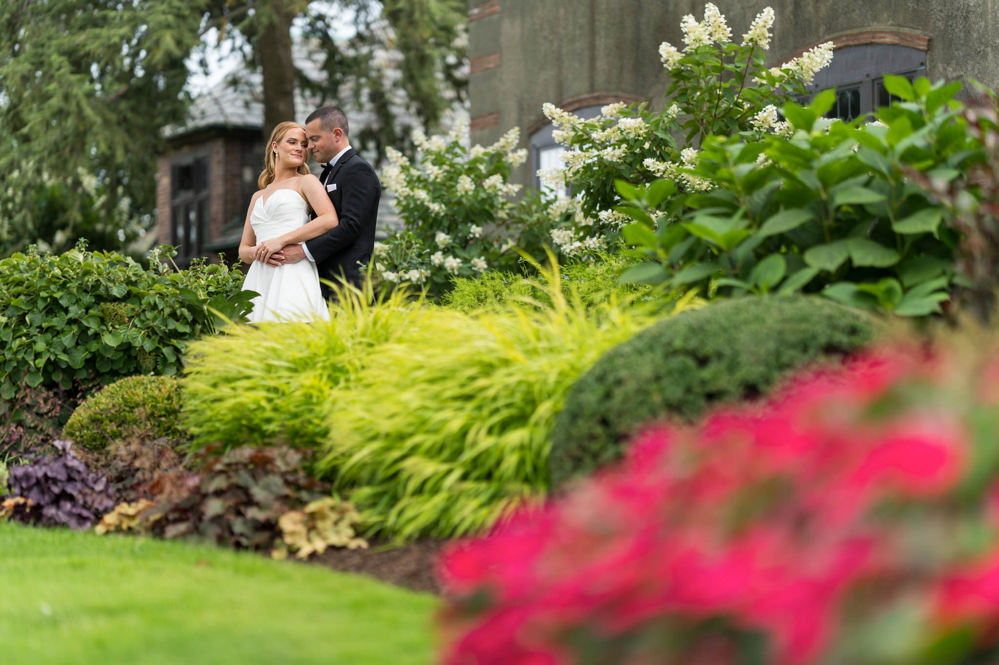 A bride and groom embrace in the gardens of their Country Club of Detroit wedding.  
