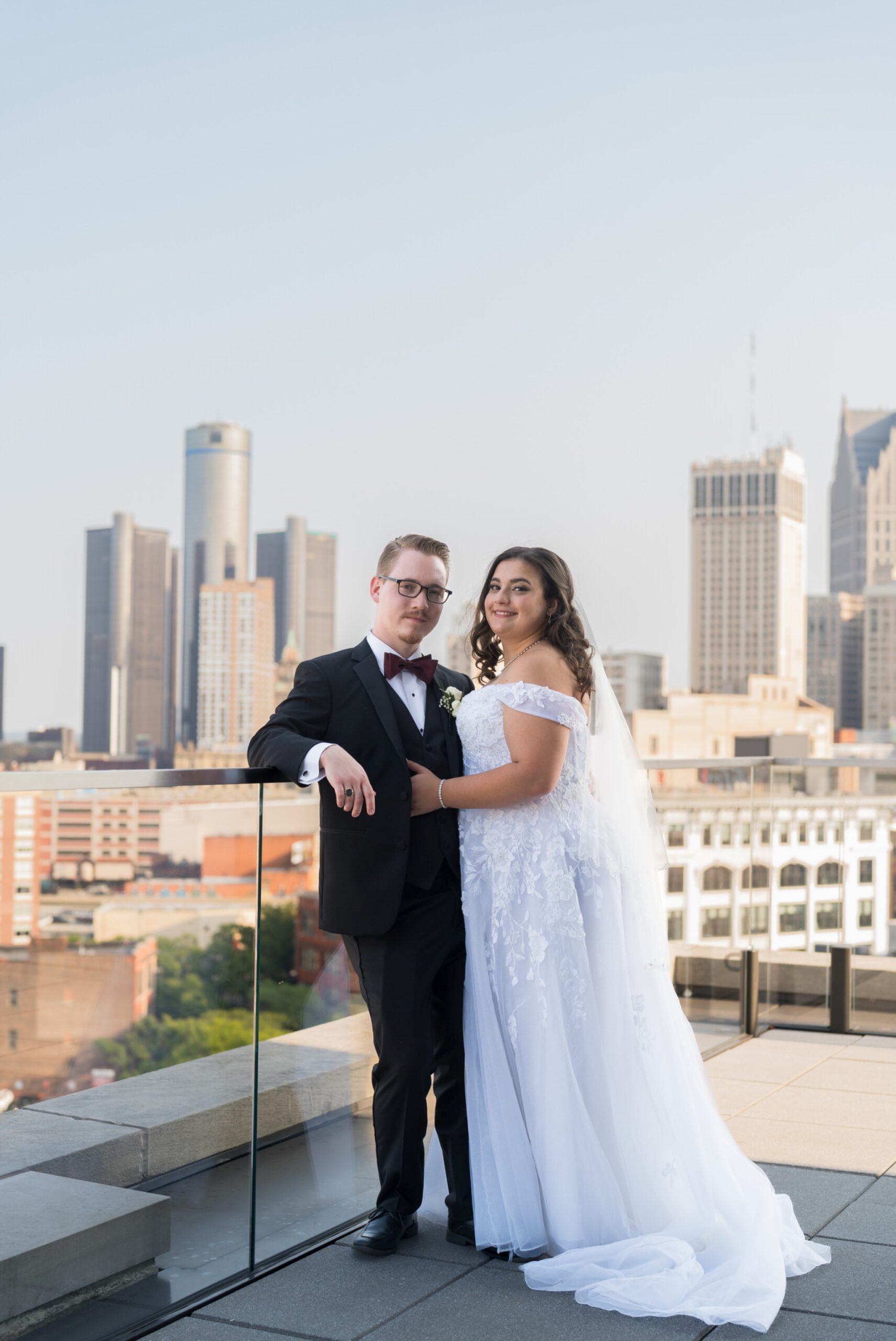 A couple embraces with the Detroit city skyline behind them at their Detroit Athletic Club wedding.  