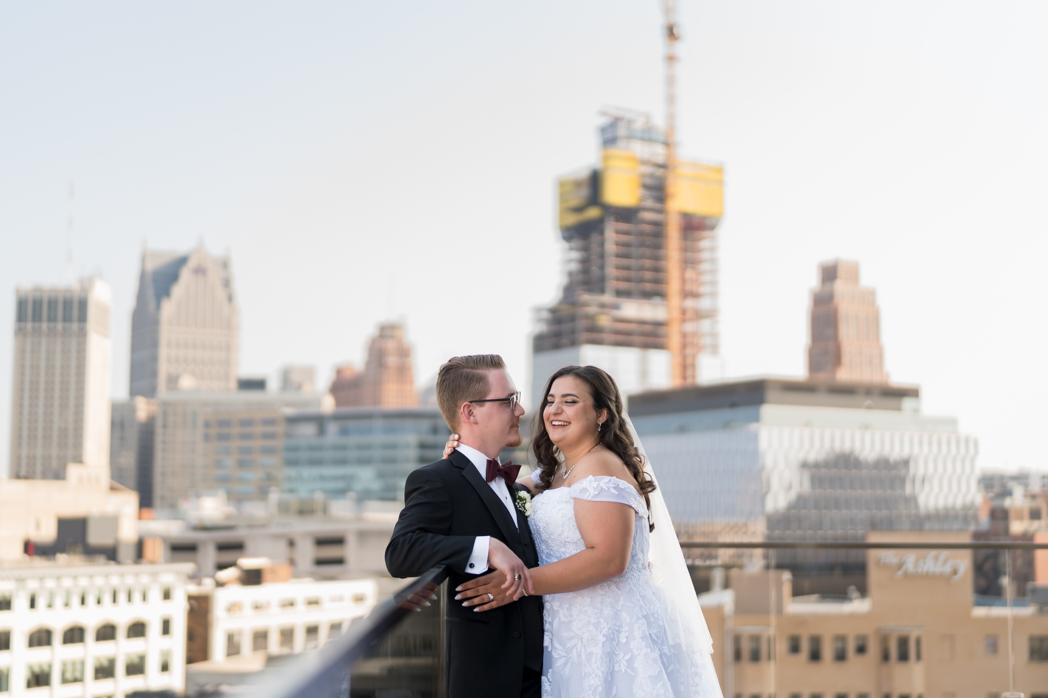 A couple laughs and embraces on the rooftop at their Detroit Athletic Club wedding.  