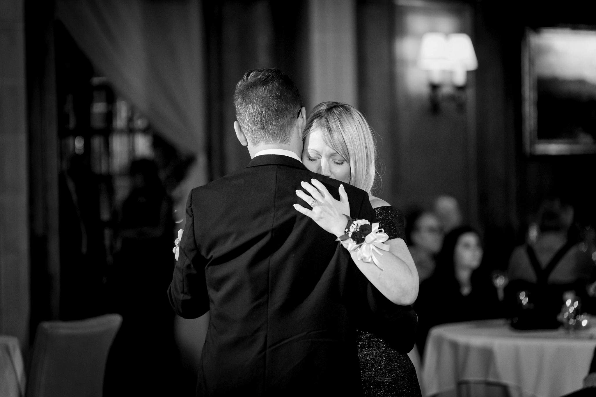 A mom squeezes her son while slow dancing at a Detroit Athletic Club wedding.