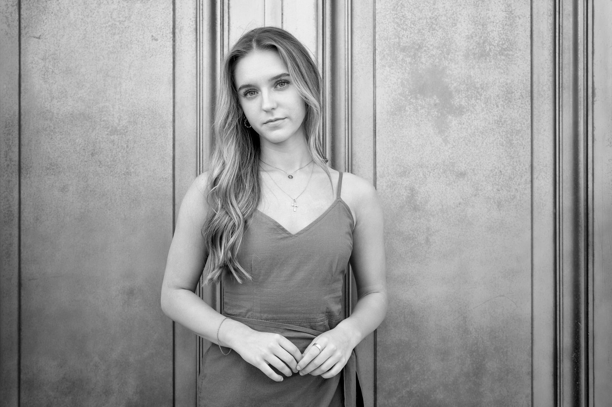a black and white portrait in front of a door at a DIA senior photo session.