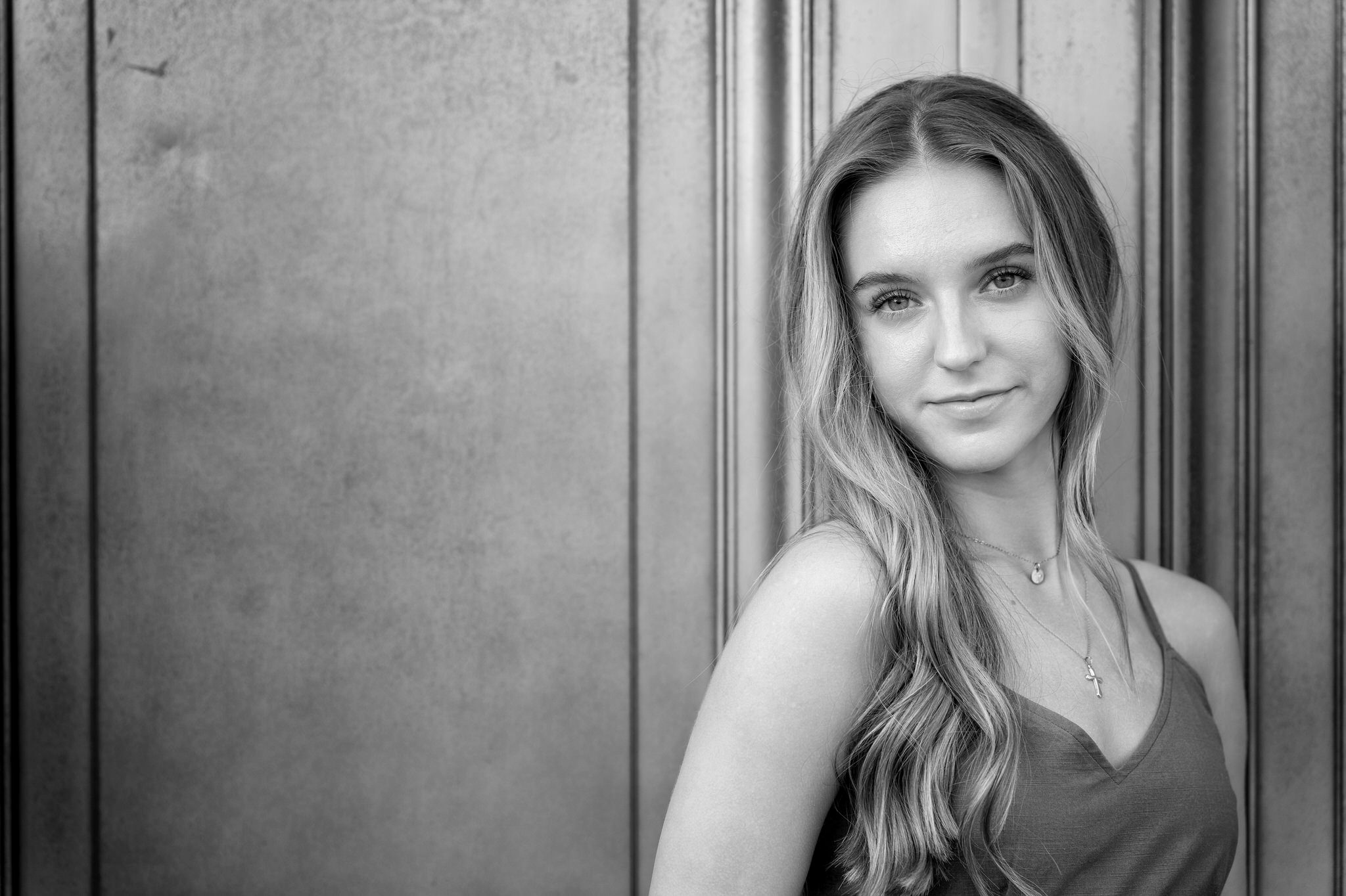 a black and white portrait of a female in front of a door at a DIA senior photo session.