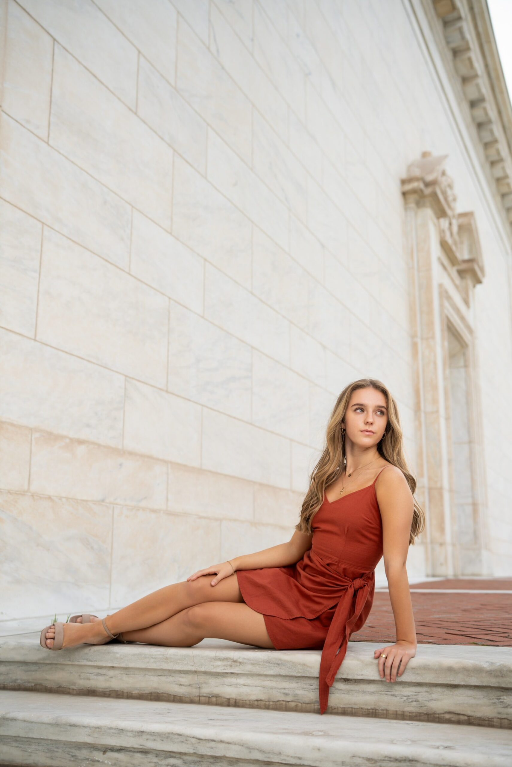 Lounging on the steps, a female teenager poses during her DIA senior photos. 