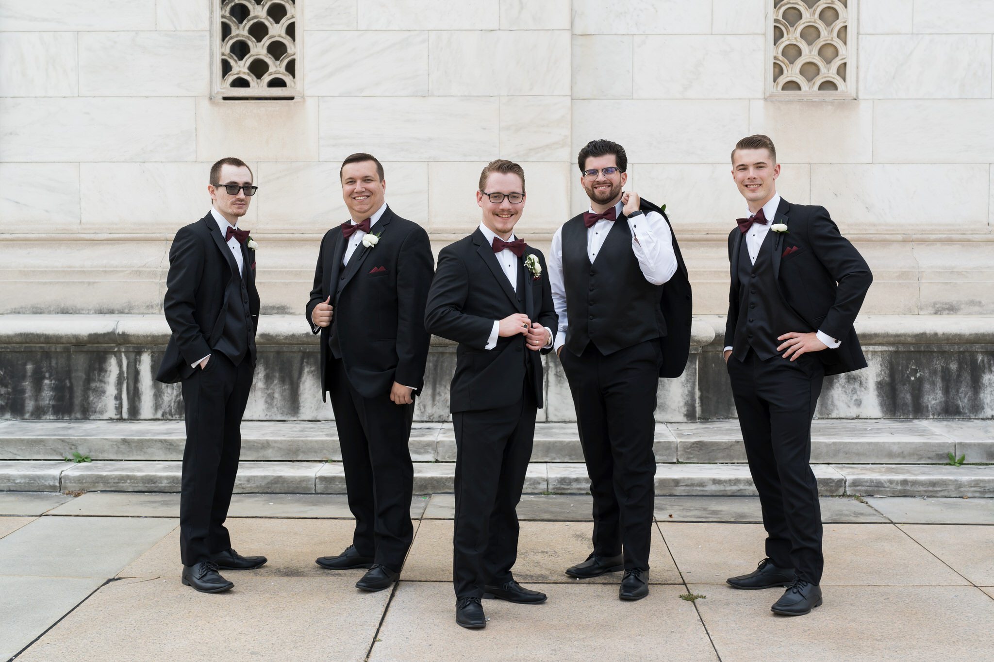 Groomsmen pose outside of the Detroit public library on a wedding day.  