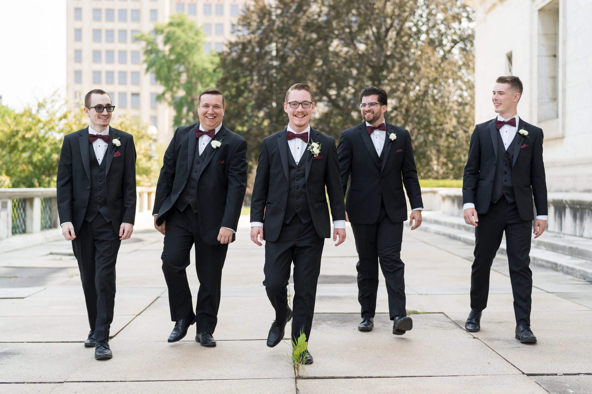 Groomsmen walk outside of the Detroit public library on a wedding day.  