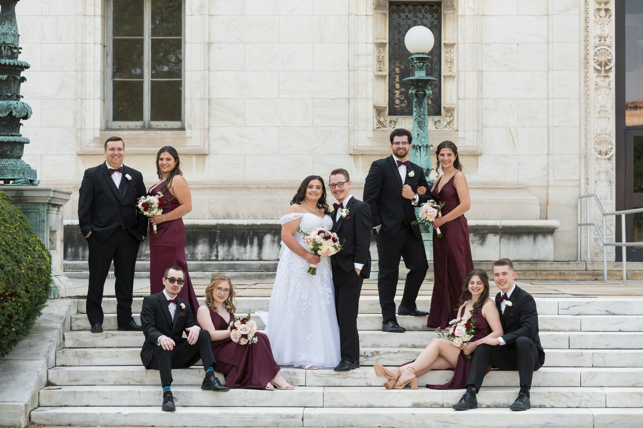 A bridal party poses on the steps of the Detroit public library on a wedding day.  