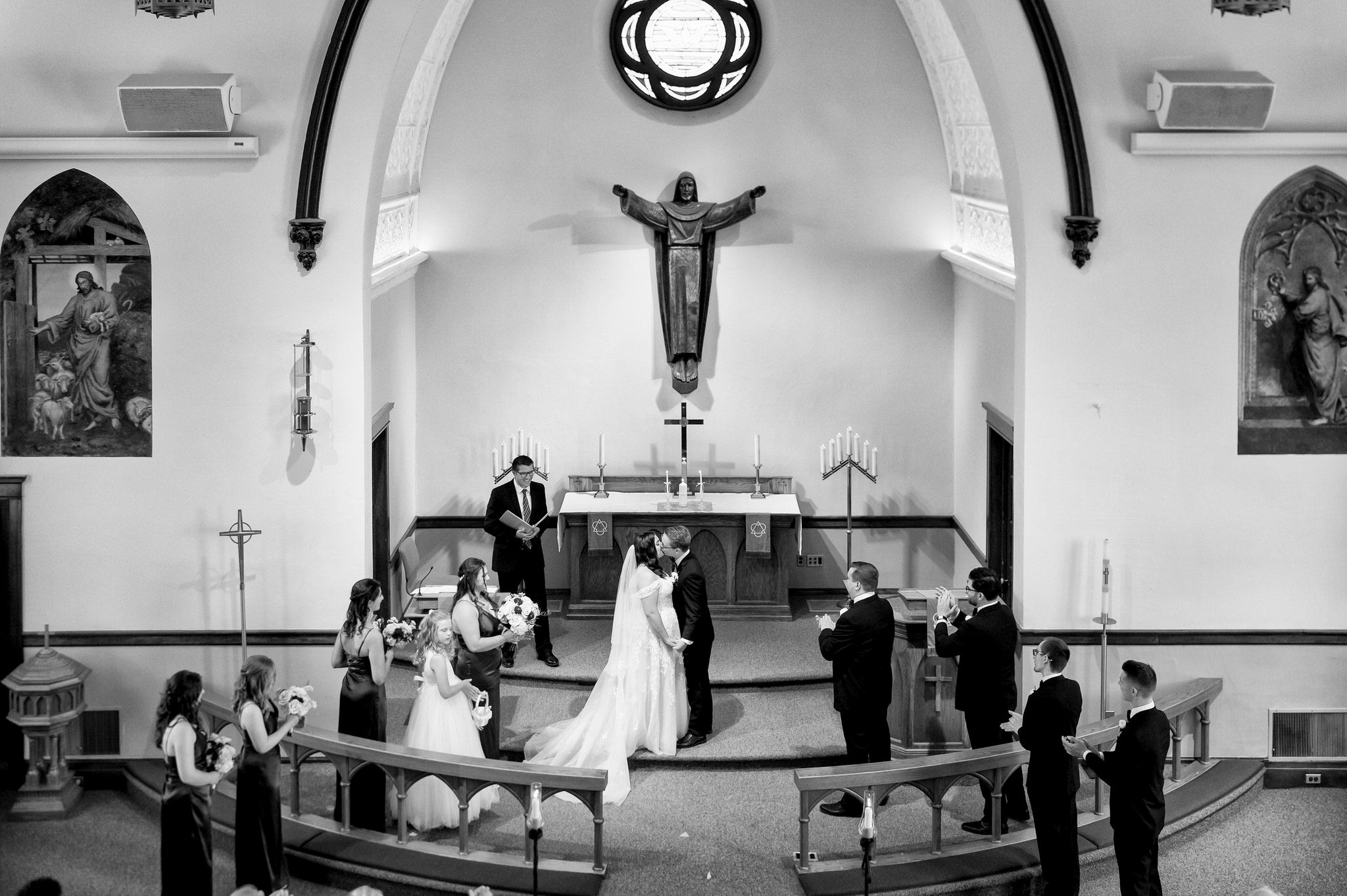 A shot from the balcony, the bride and groom kiss at the altar on their wedding day at Immanuel Lutheran Church in Macomb, MI. 