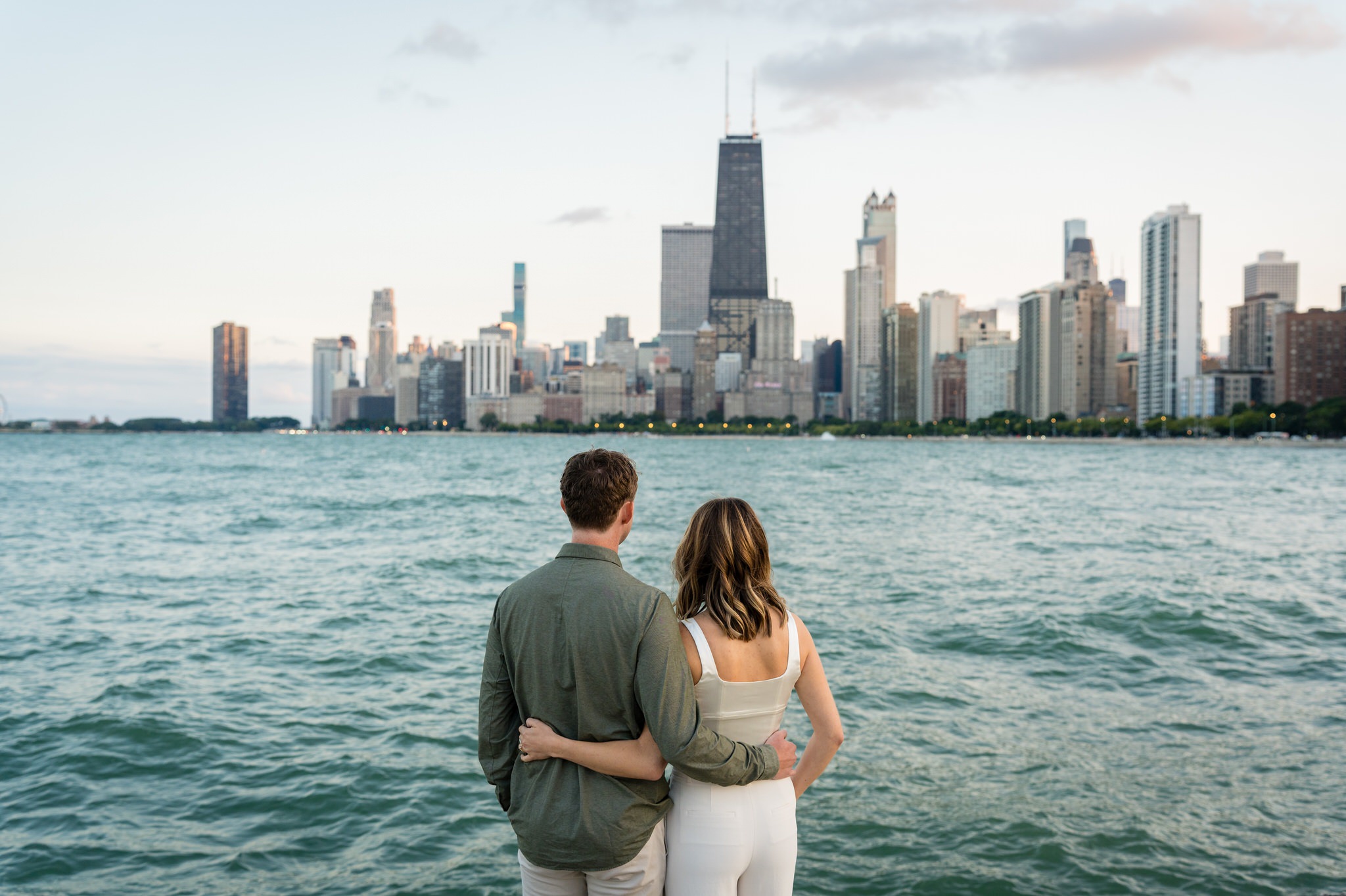 A couple poses at North Ave Beach with the skyline in the background of their Lincoln Park Chicago engagement session. 