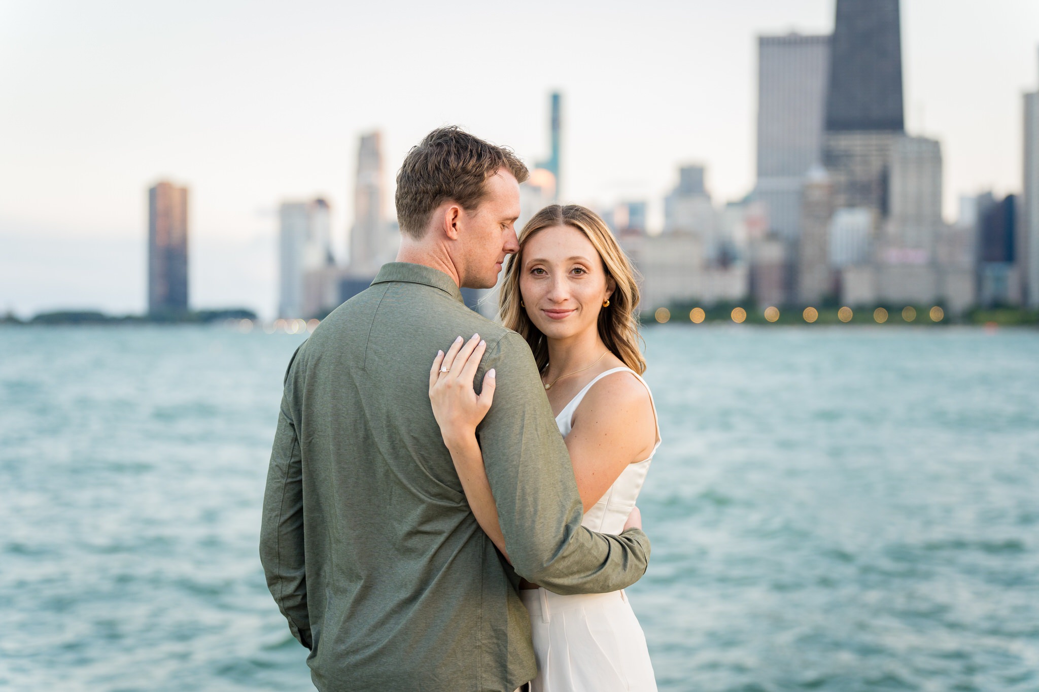 A couple poses at North Ave Beach  in Chicago with the skyline in the background during their engagement session. 