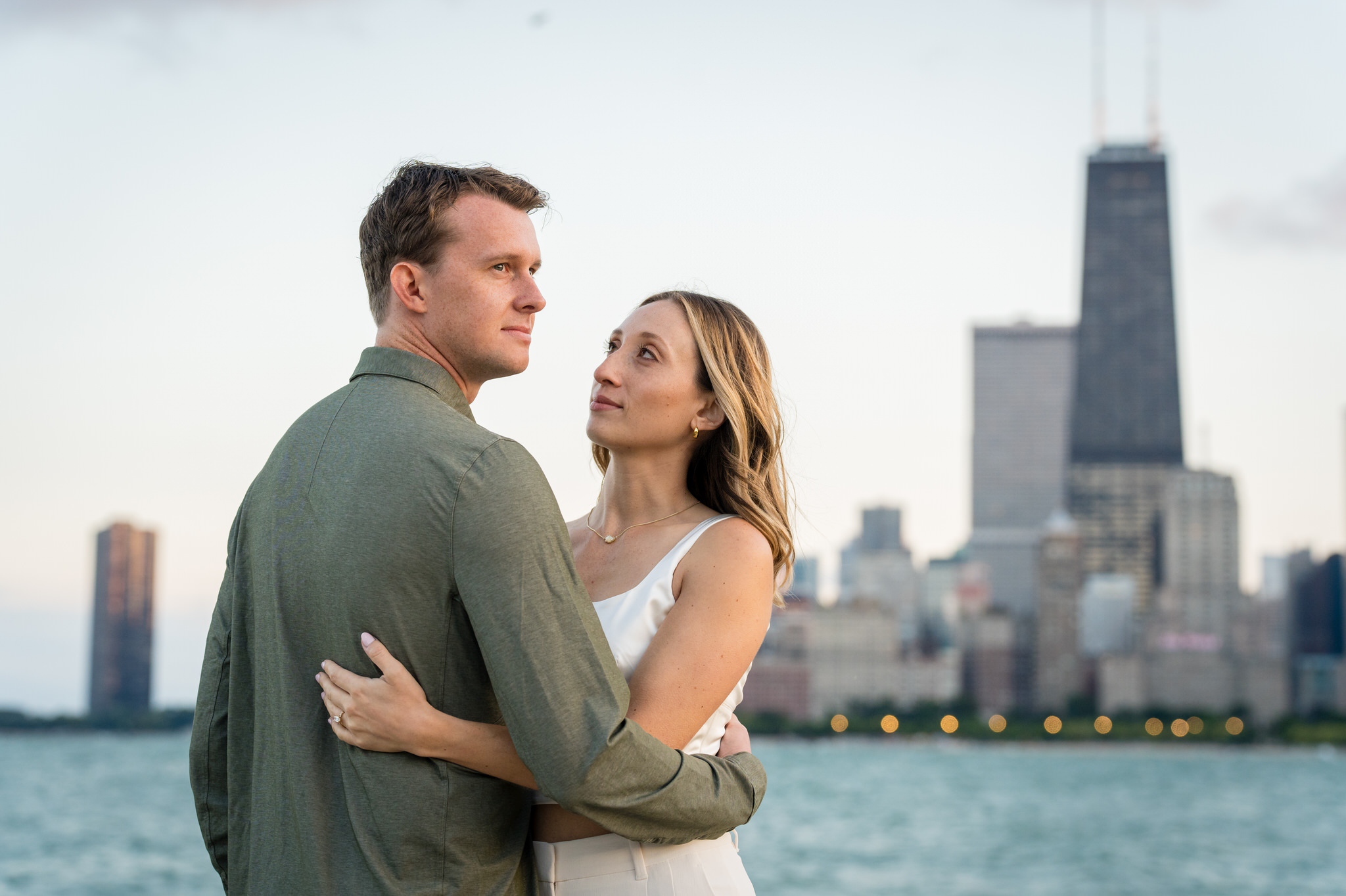 A couple poses at North Ave Beach  in Chicago with the skyline in the background during their engagement session. 