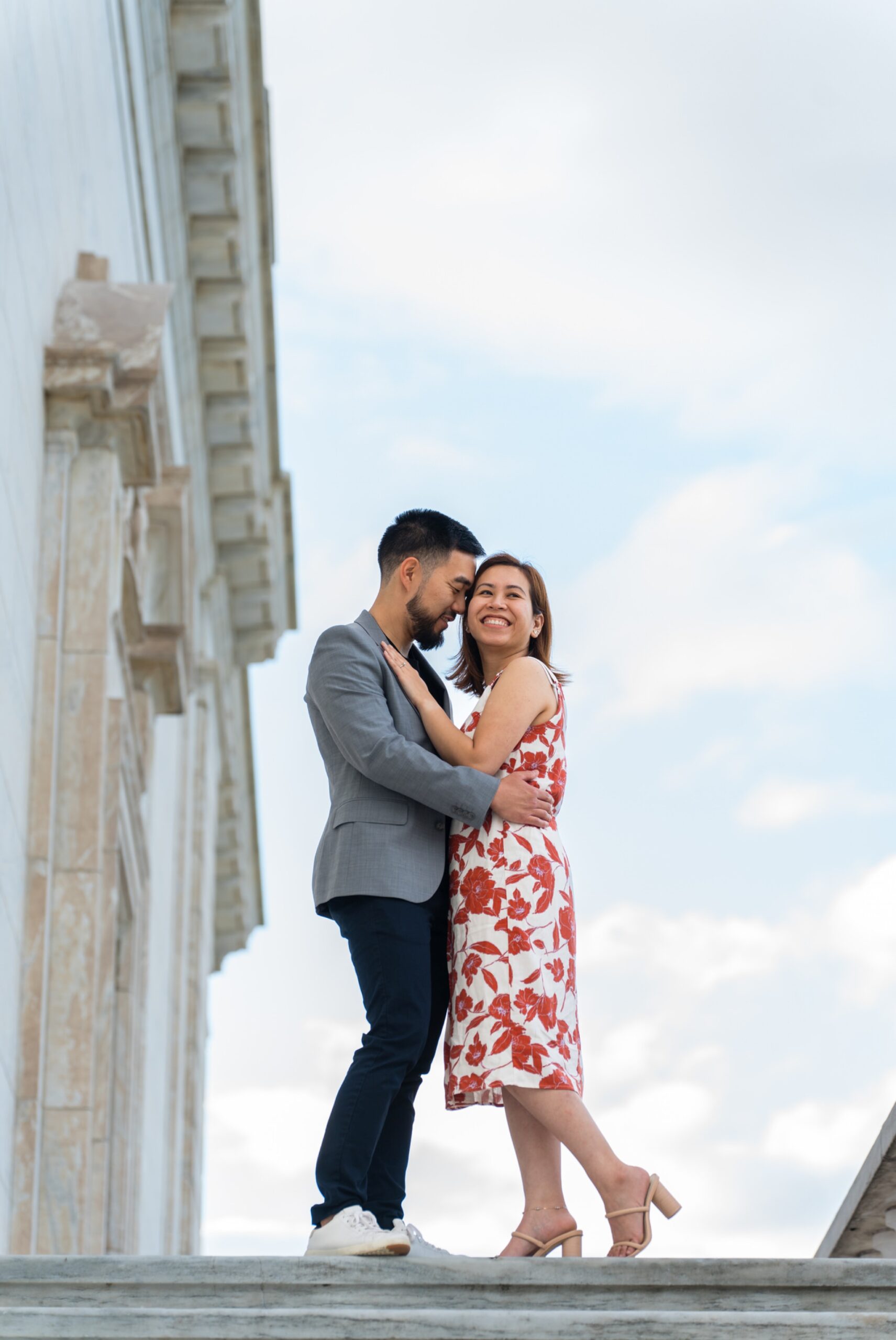 A couple poses, standing atop the steps of the DIA during an engagement shoot.  