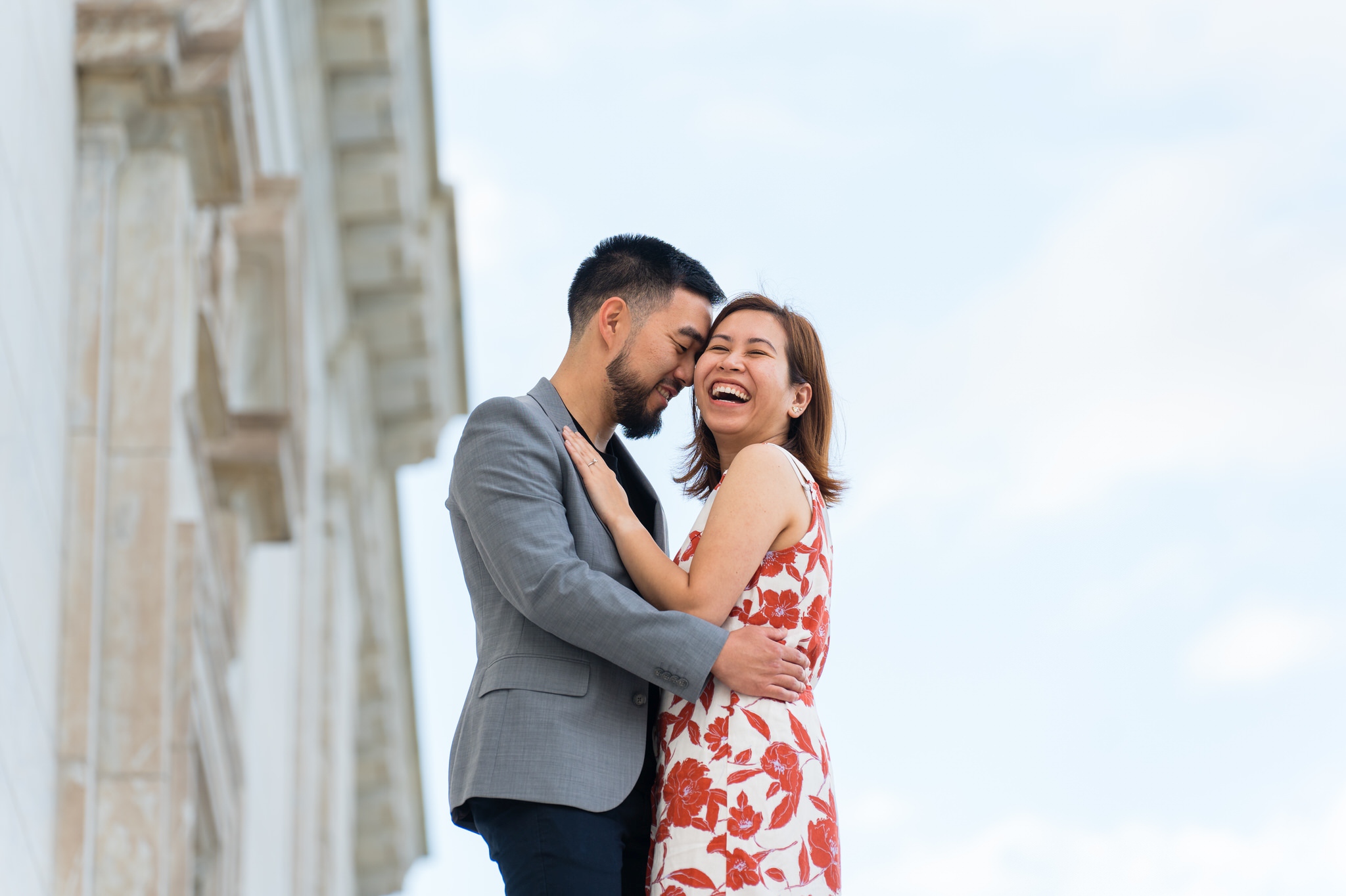 A couple laughs, standing atop the steps of the DIA during an engagement shoot.  
