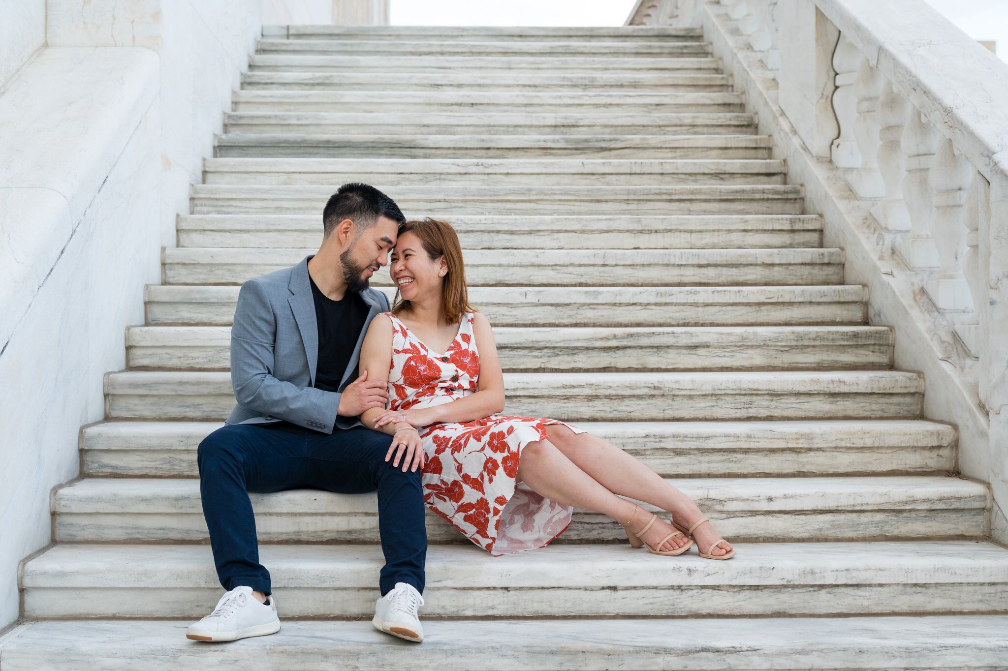 A couple sits on the steps of the DIA during an engagement shoot.  