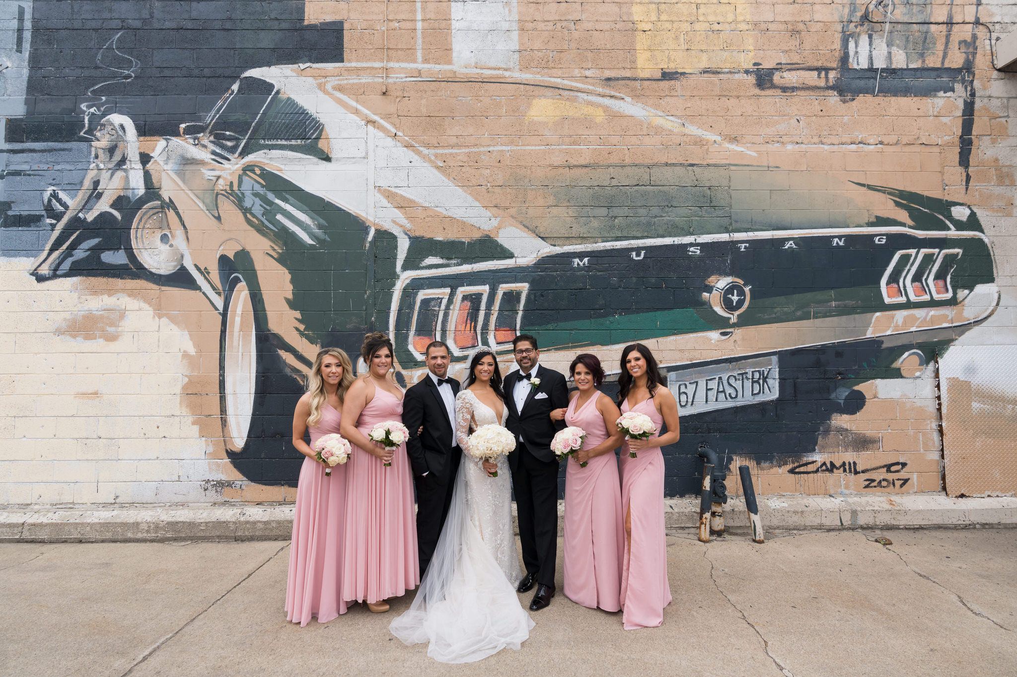 A bridal party poses in front of a large mural on their wedding day in Eastern Market, Detroit. 