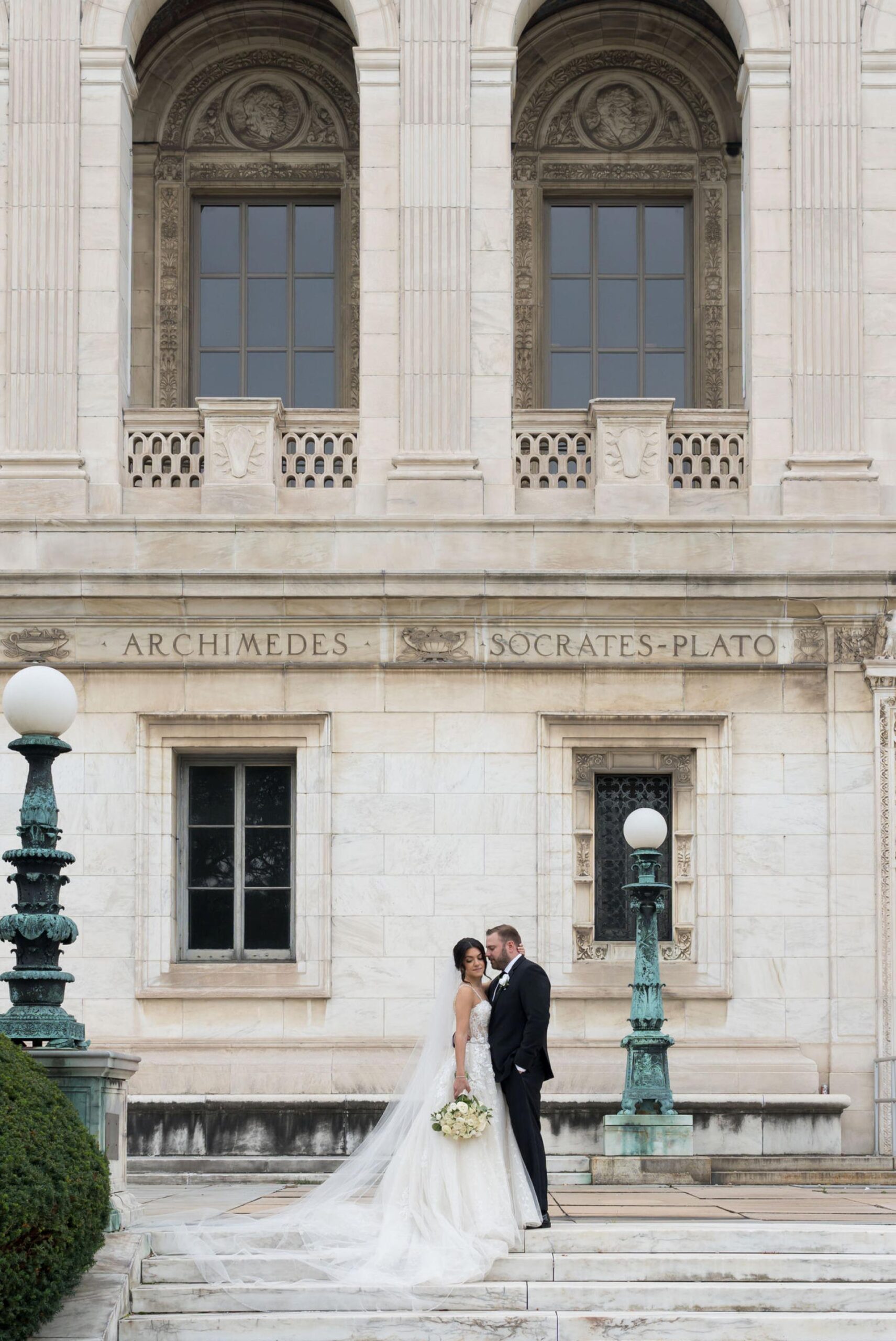A bride and groom pose on steps in downtown Detroit on their wedding day.  