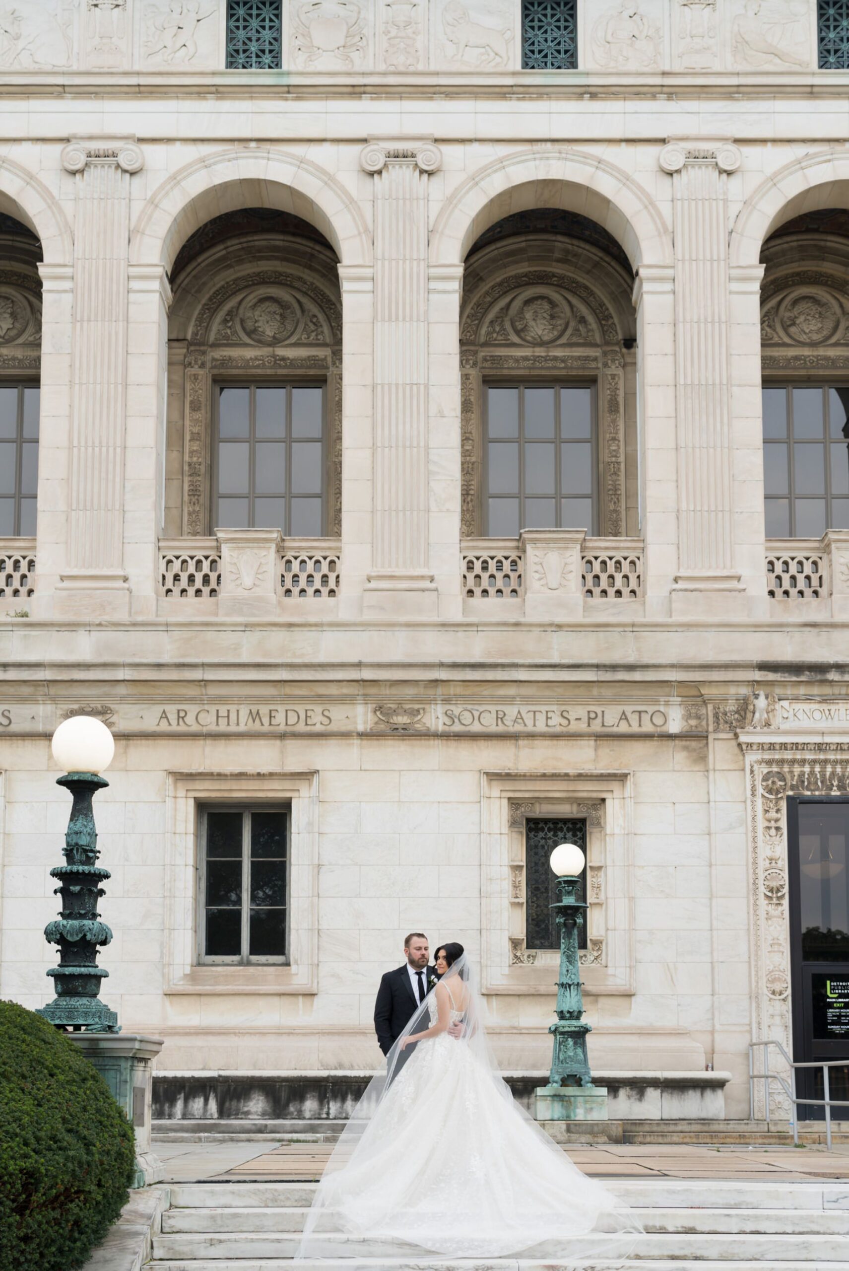 A bride and groom pose on steps of the Detroit Public Library on Woodward on their wedding day.  