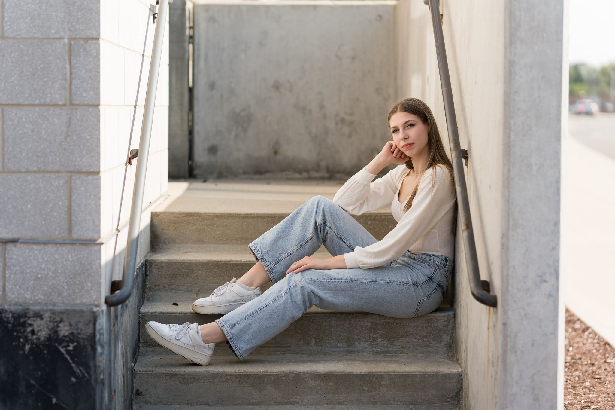 A teen poses for her Detroit senior pictures in a short stairwell.