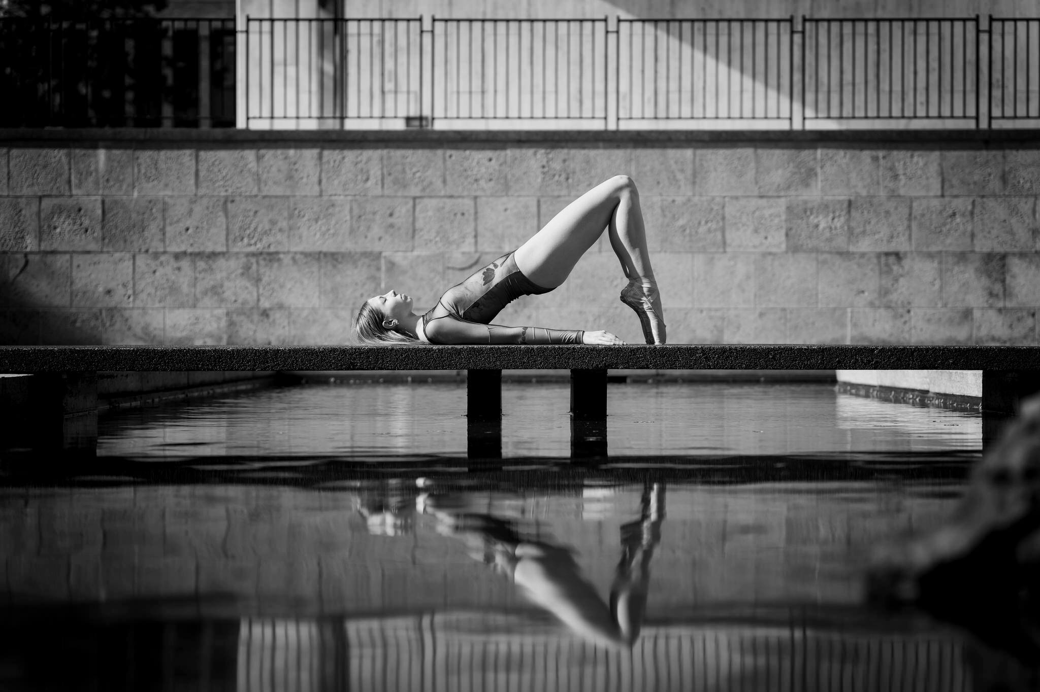 A dancer wearing a leotard poses on Wayne State University's reflection pool for her Detroit senior pictures.  