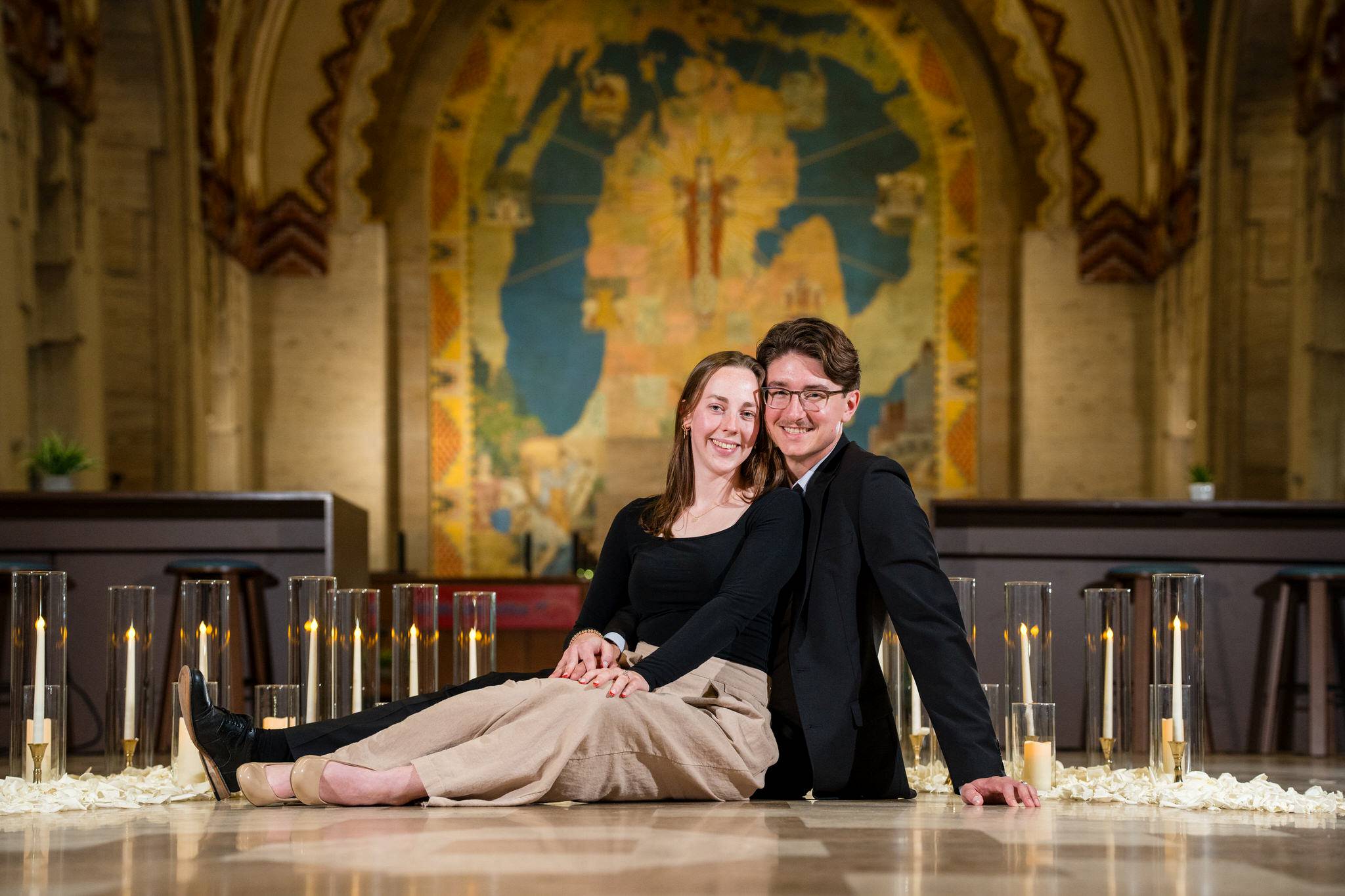 A couple sits on the ground and touches following their Guardian Building proposal. 