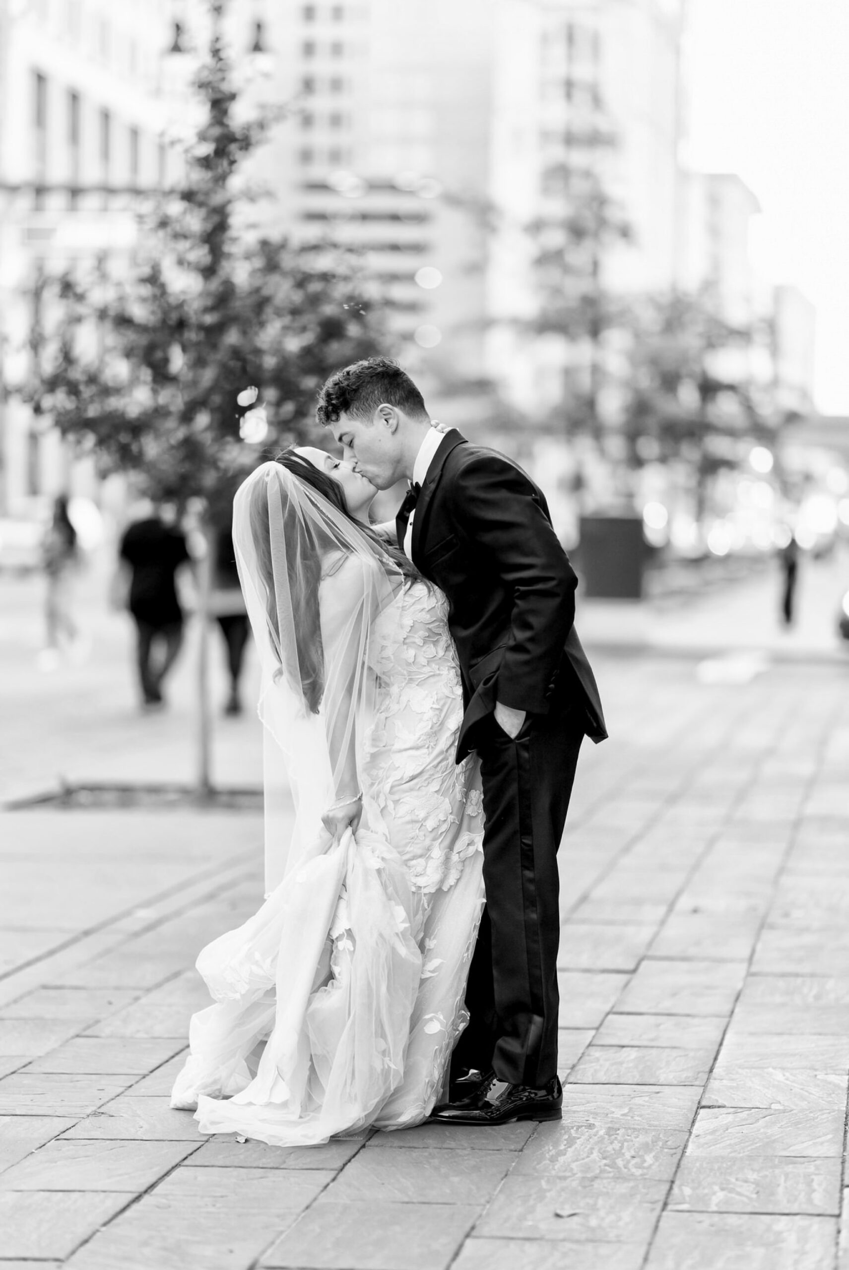 A newlywed couple stops and kisses on Woodward Ave after celebrating their San Morello wedding. 