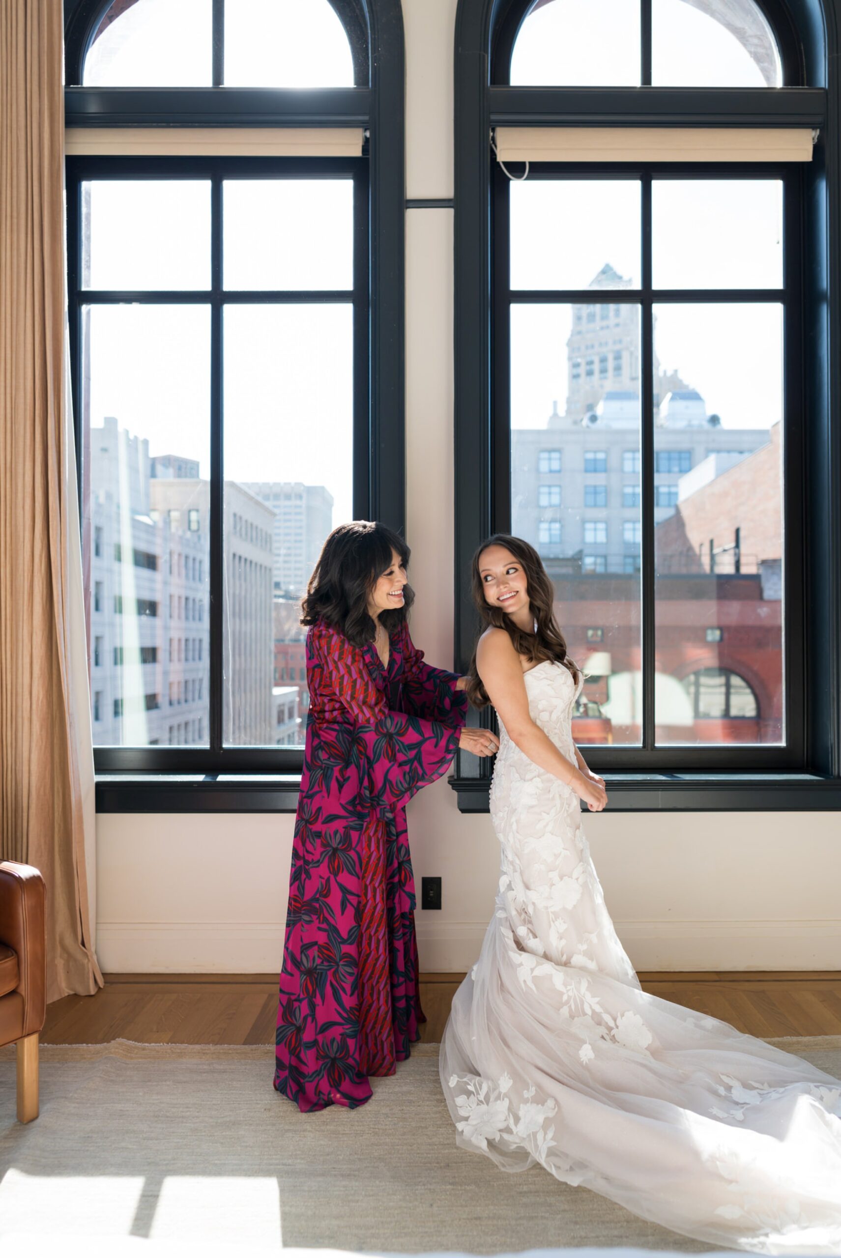 A bride gets ready with the help of her mom in front of a window at the Shinola Hotel before her San Morello wedding later that day. 