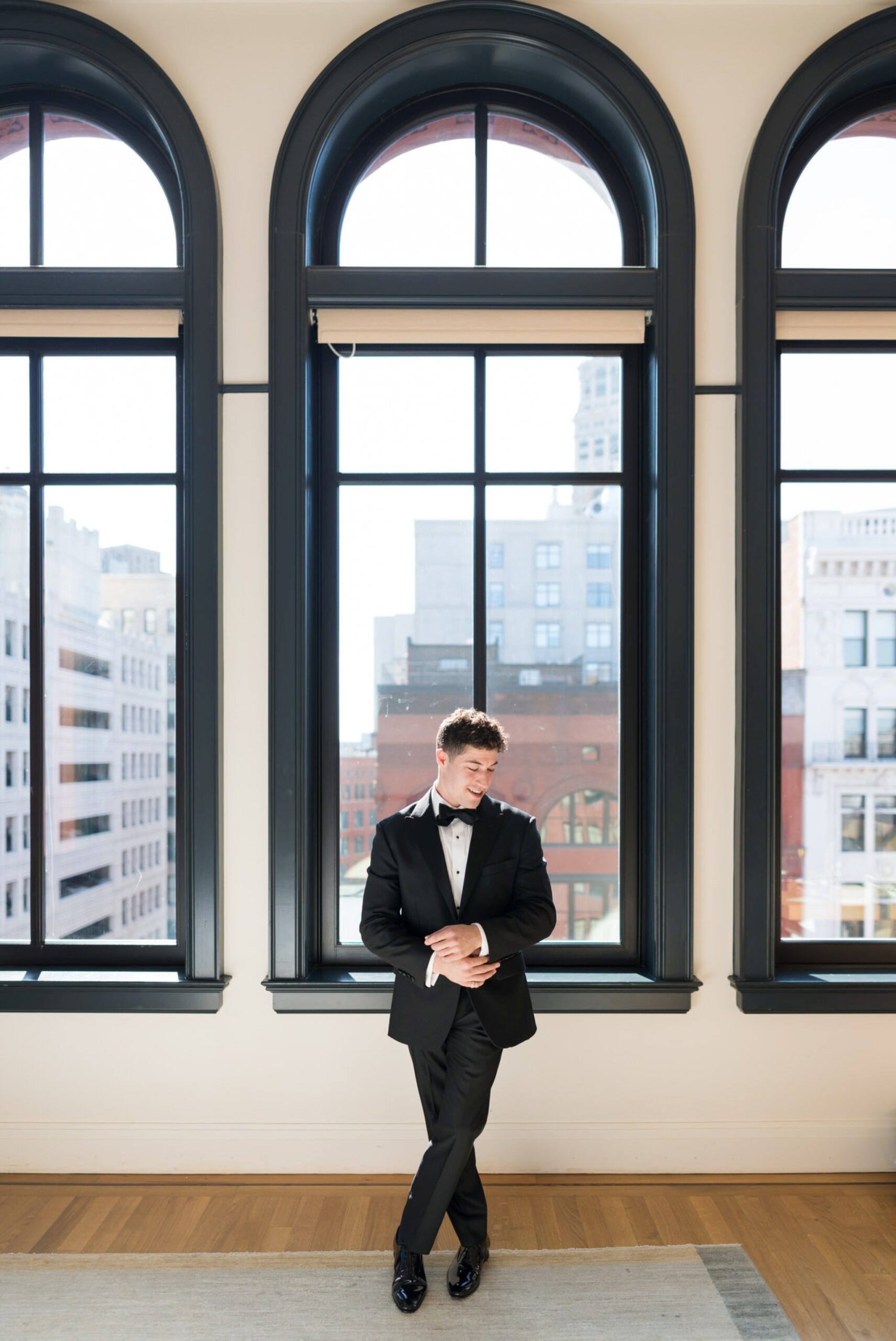 A groom gets ready in front of a window at the Shinola Hotel in Detroit before his San Morello wedding.  