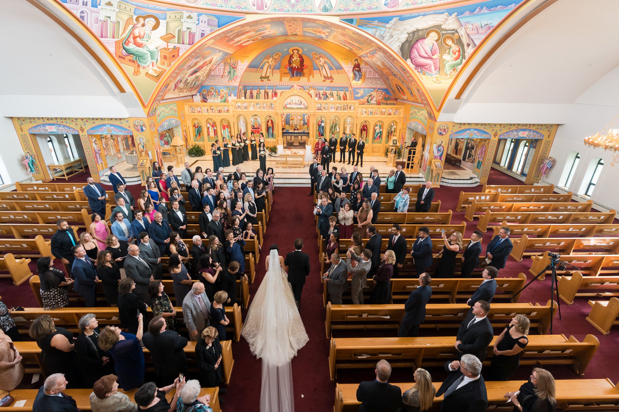 A bride walks down the aisle with her dad at an Assumption Greek Orthodox wedding in St. Clair Shores, Michigan.