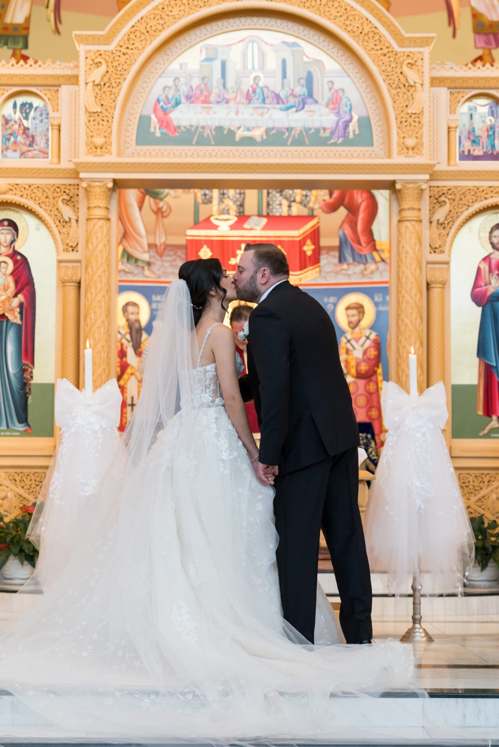 A bride and groom kiss at the altar of their Assumption Greek Orthodox wedding in St. Clair Shores, Michigan.