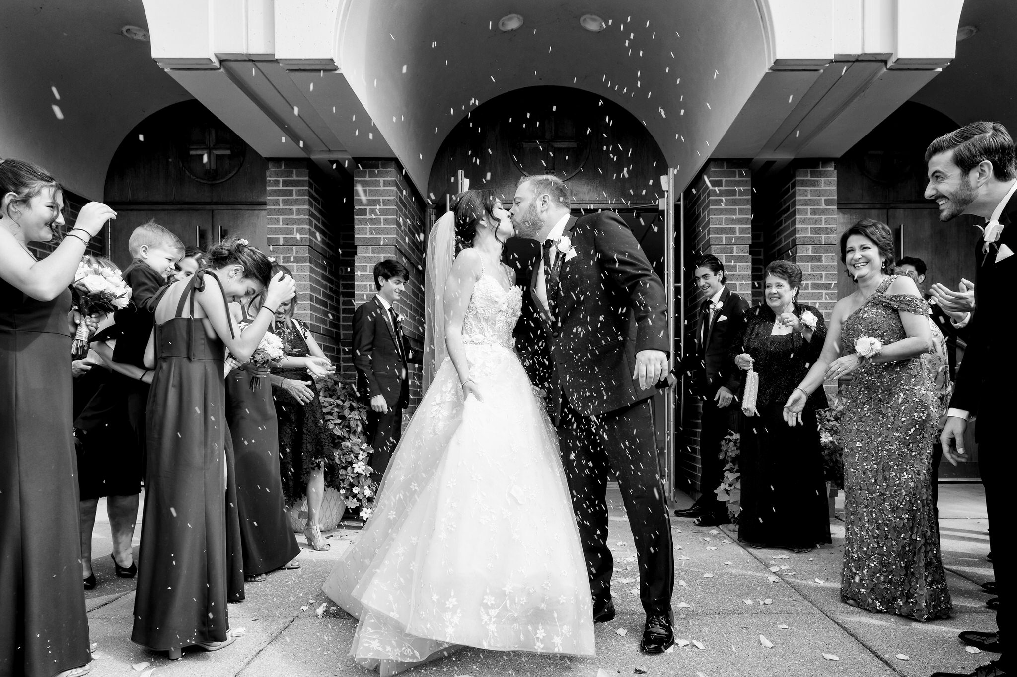 A bride and groom kiss outside of their Assumption Greek Orthodox wedding in St. Clair Shores, Michigan during a grand exit. 