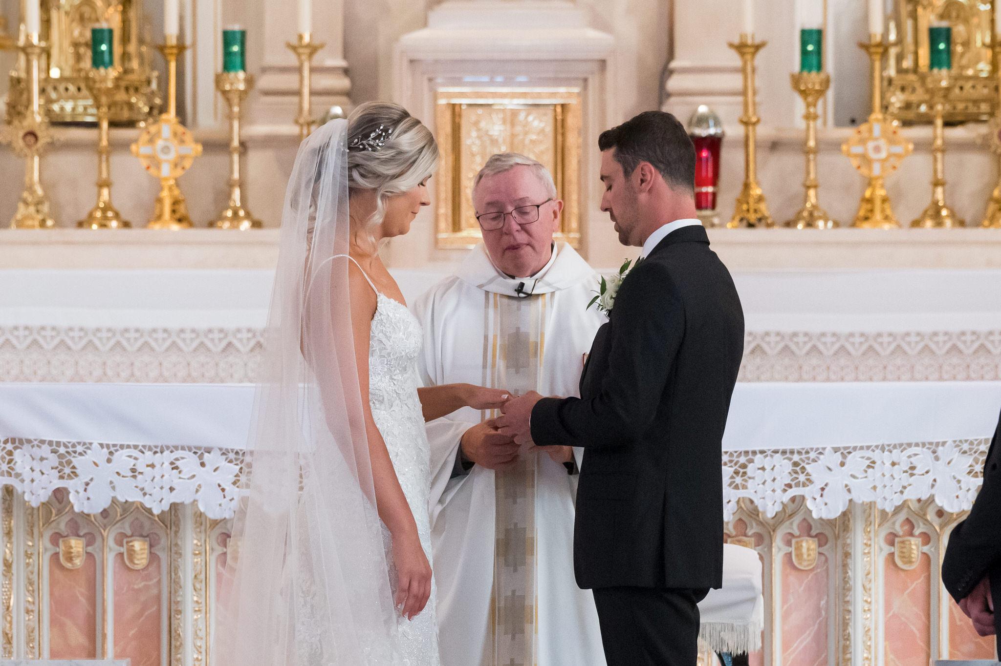 A bride and groom exchange rings at the altar of Detroit's Sweetest Heart of Mary Catholic Church on their wedding day.  