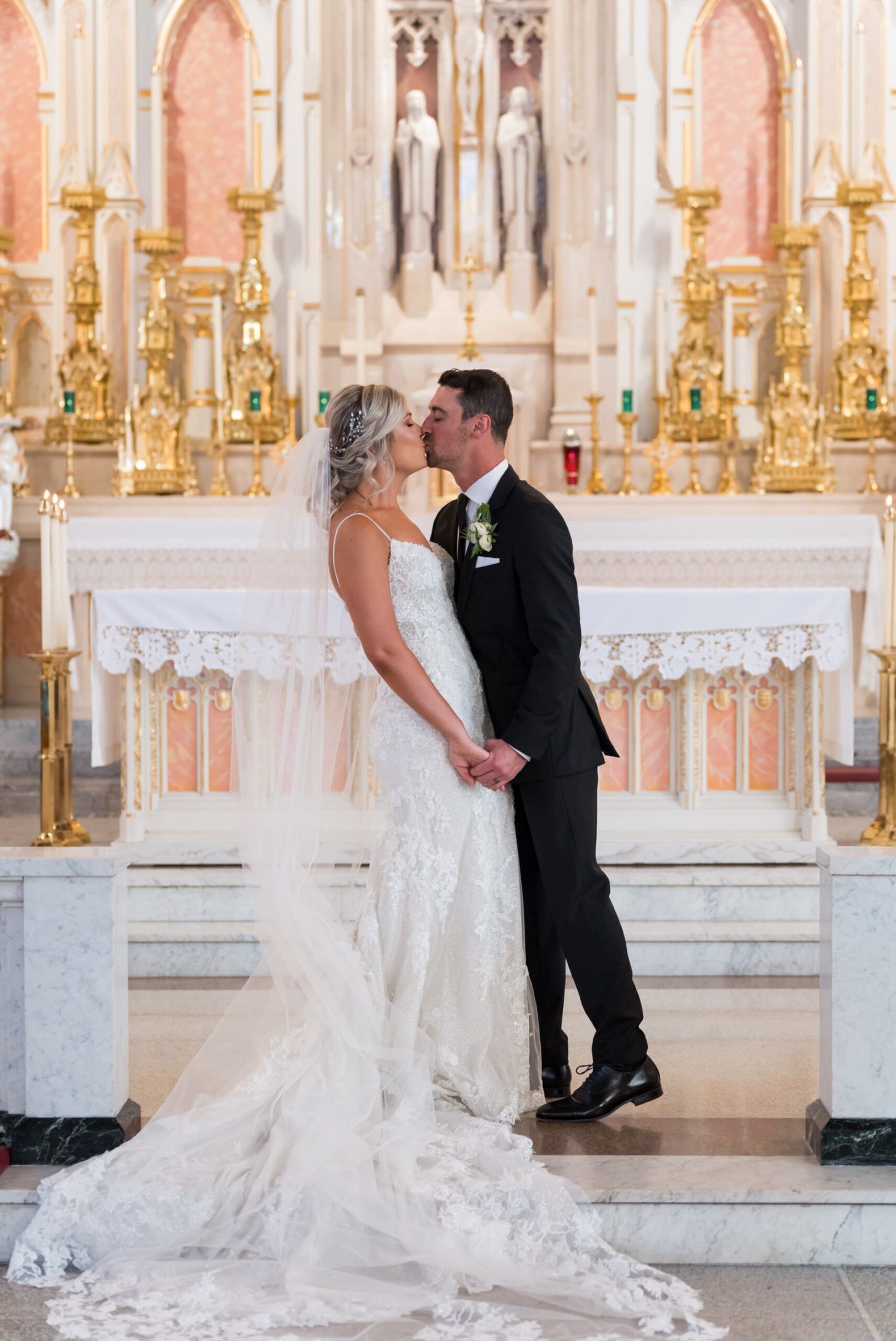 A bride and groom kiss at the altar of Detroit's Sweetest Heart of Mary Catholic Church on their wedding day.  