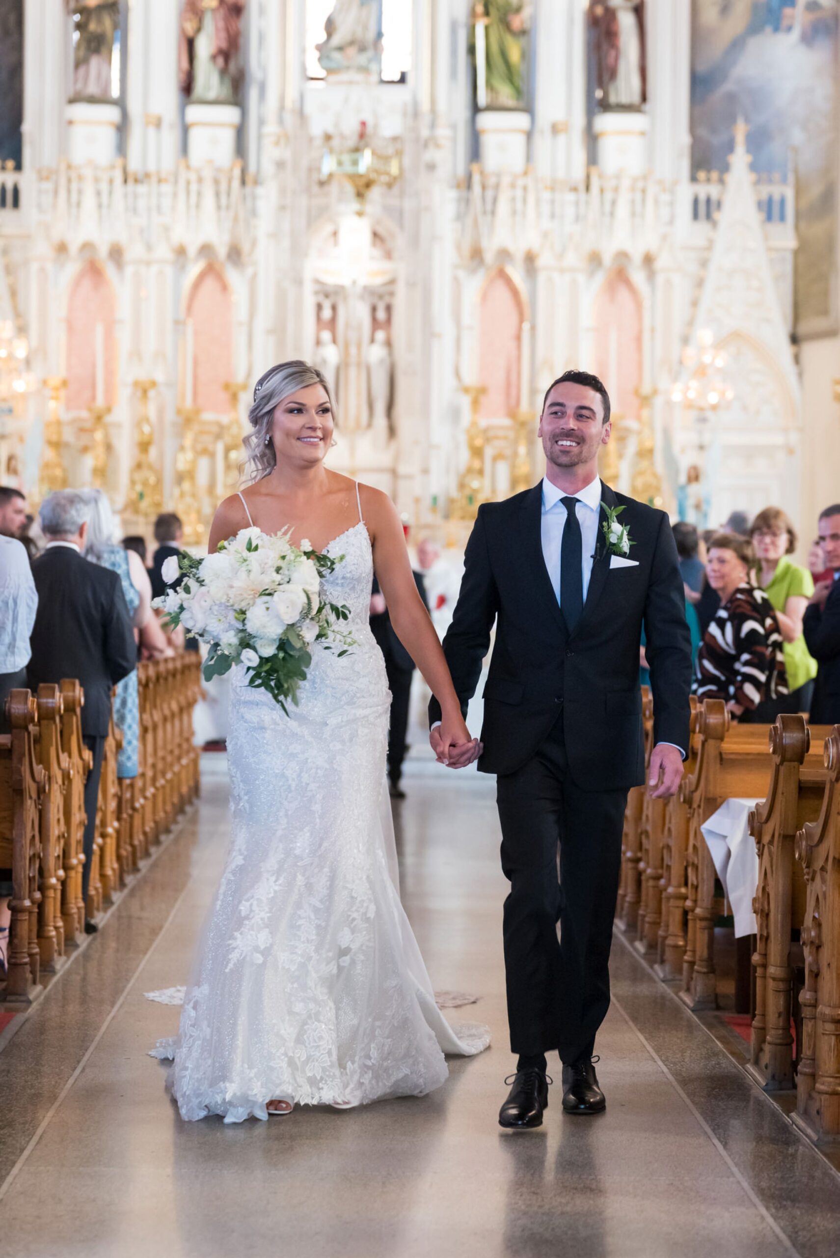 A bride and groom walk down the center aisle of Detroit's Sweetest Heart of Mary Catholic Church on their wedding day.  